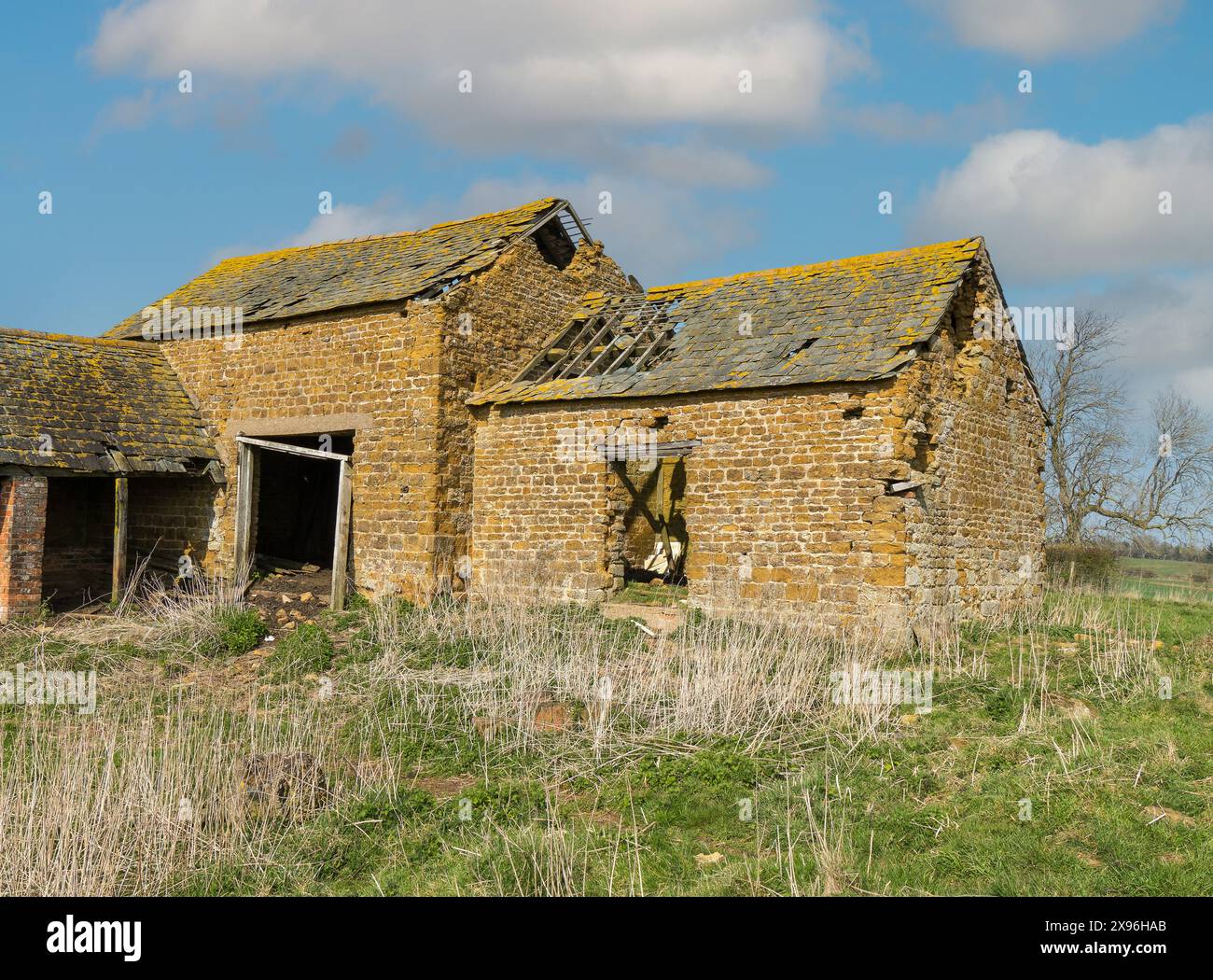 Alte ruinierte Bauernscheune aus rotem Backstein mit beschädigtem Schieferdach mit Löchern und fehlenden Schiefern, Leicestershire, England, Großbritannien Stockfoto