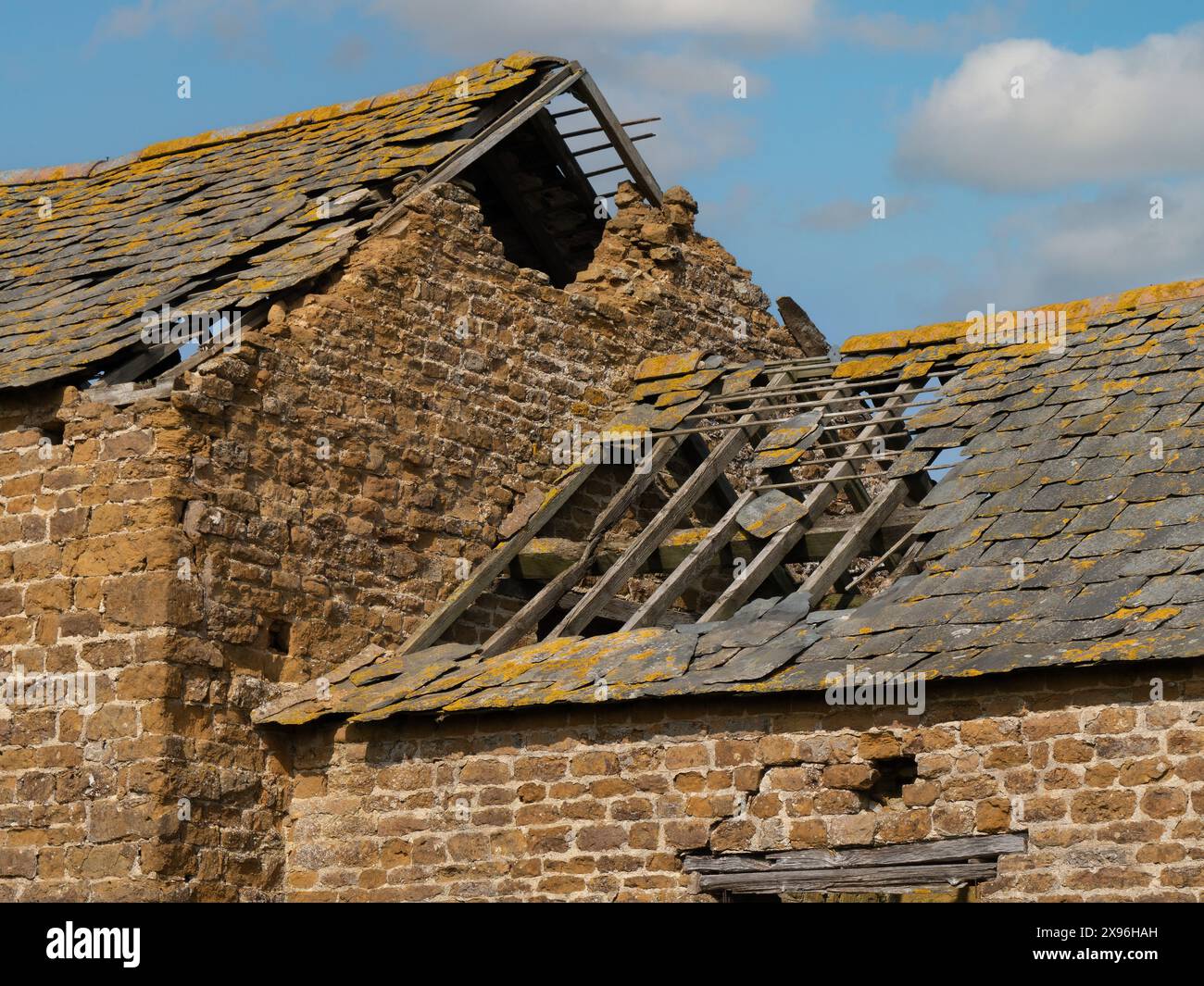 Alte ruinierte Bauernscheune aus rotem Backstein mit beschädigtem Schieferdach mit Löchern und fehlenden Schiefern, Leicestershire, England, Großbritannien Stockfoto