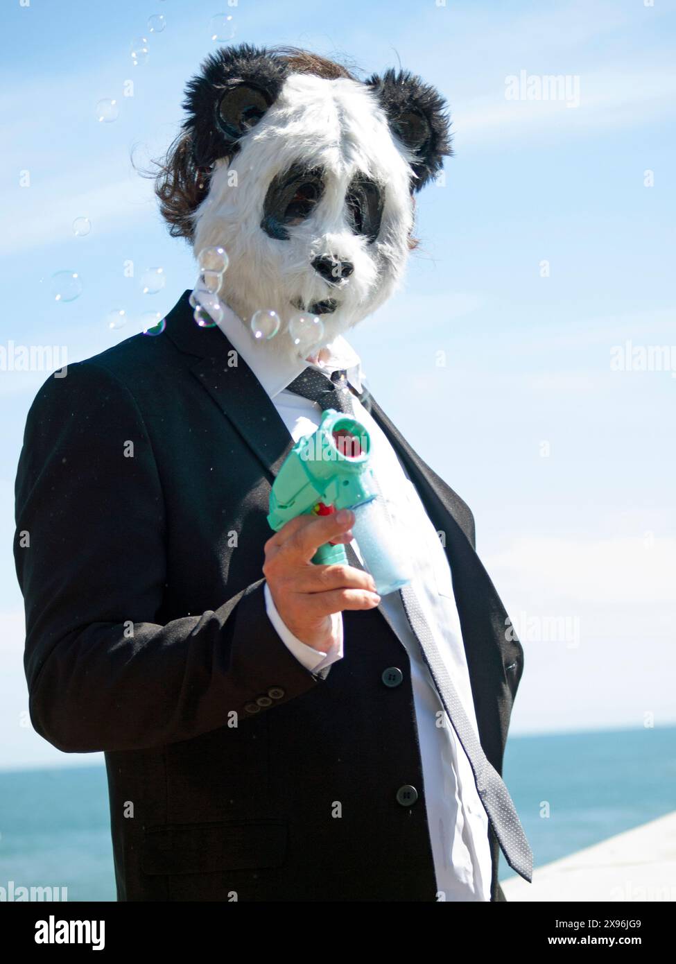 Ein Mann trägt eine Pandabärenmaske an der Küste von Brighton Stockfoto