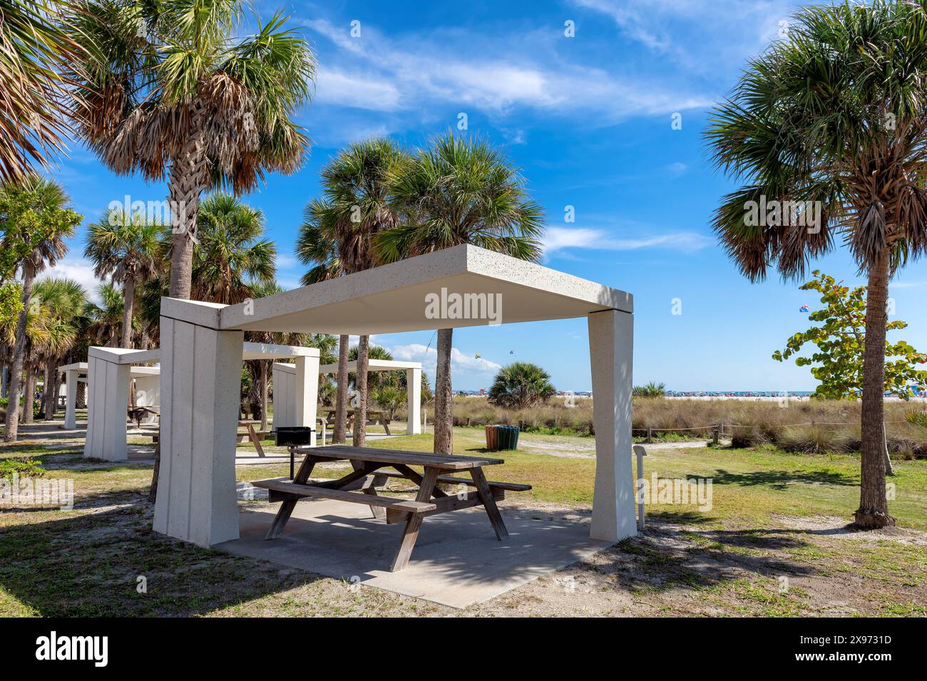 Picknicktische und Unterstände am Siesta Key Beach in Florida, wo Besucher ein Picknick unter Palmen am Meeresstrand genießen können. Stockfoto Picknicktische und Unterstände am Siesta Key Beach in Florida, wo Besucher ein Picknick unter Palmen am Meeresstrand genießen können. Stockfoto