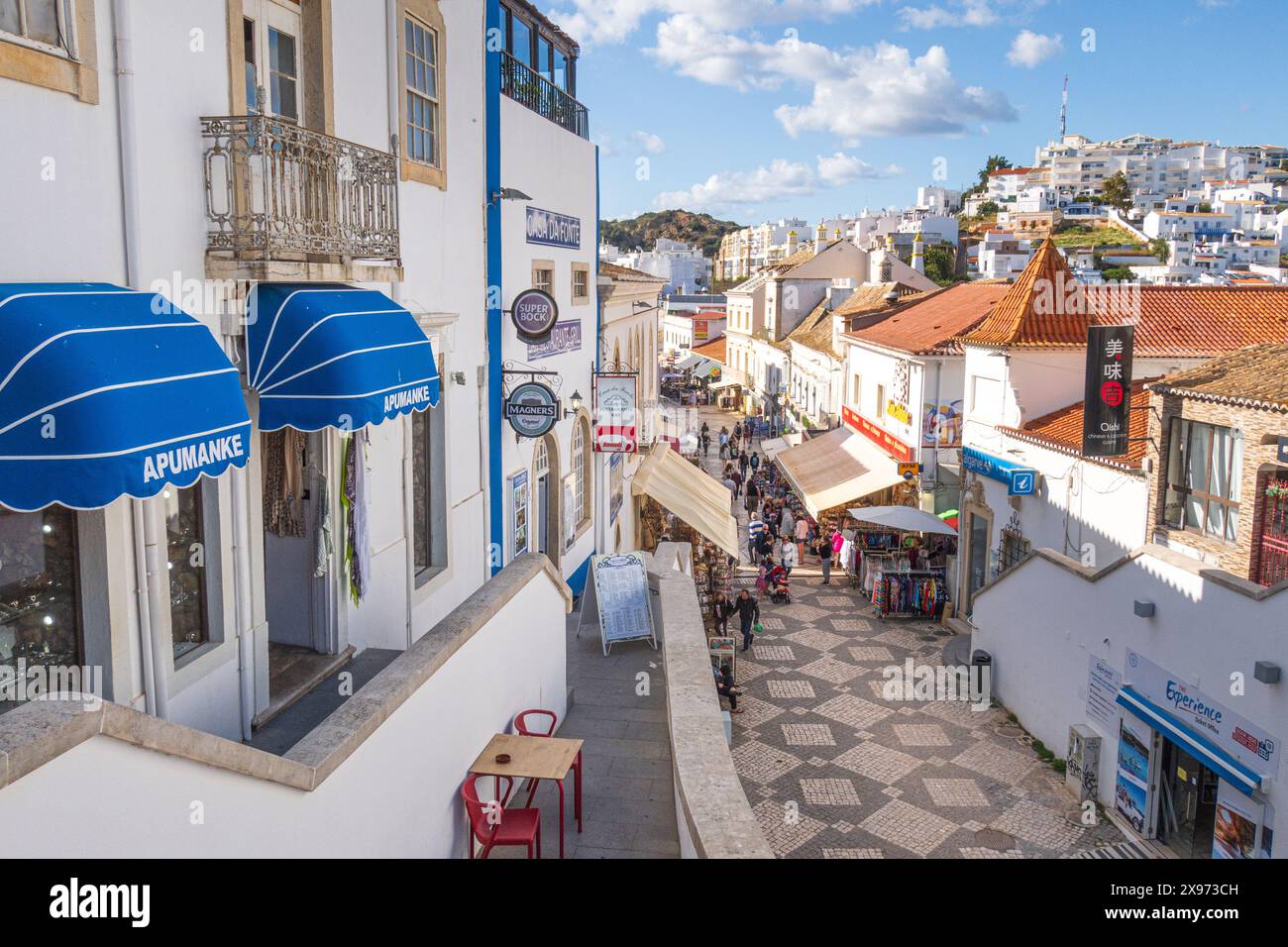 Albufeira, Portugal - 27. April 2024: Traditionelle Gebäude und Touristen fotografiert in einer Straße von Albufeira an der portugiesischen Algarve Stockfoto