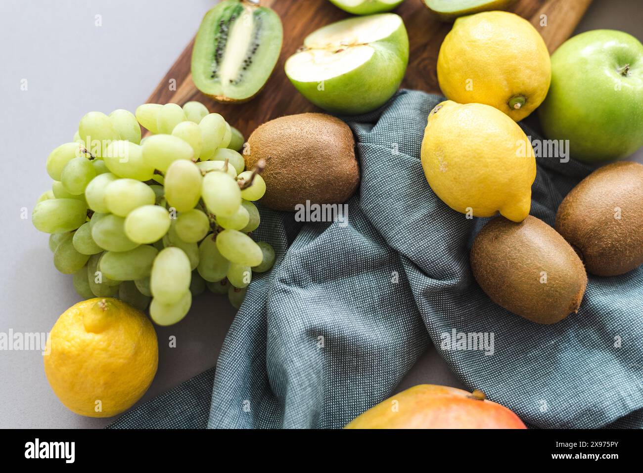 Frisches Obst, Trauben, Zitronen, Bananen, Mangos, Kiwi, und Äpfel auf einem Schneidebrett. Stockfoto