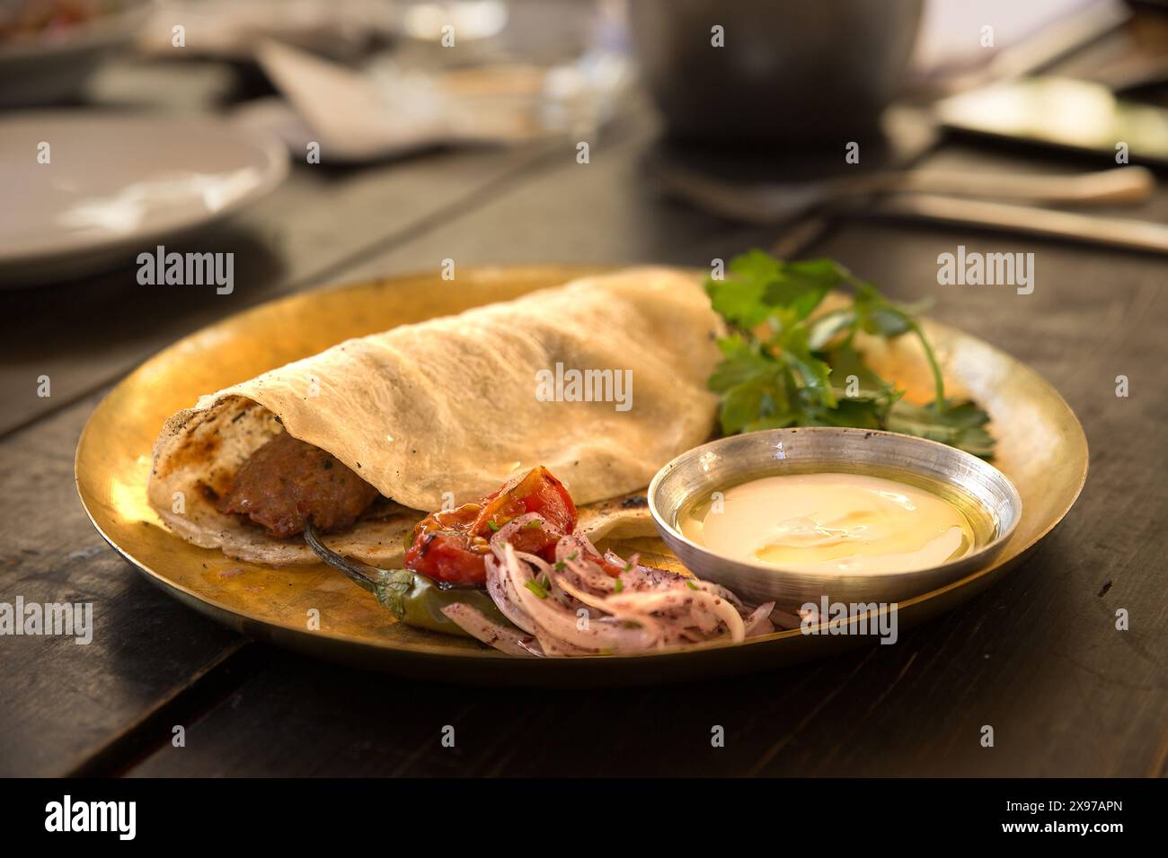 Köstliche Mahlzeit umfasst Kebab, Tahini, heißen Pfeffer und Zwiebeln auf einem Metallteller Stockfoto
