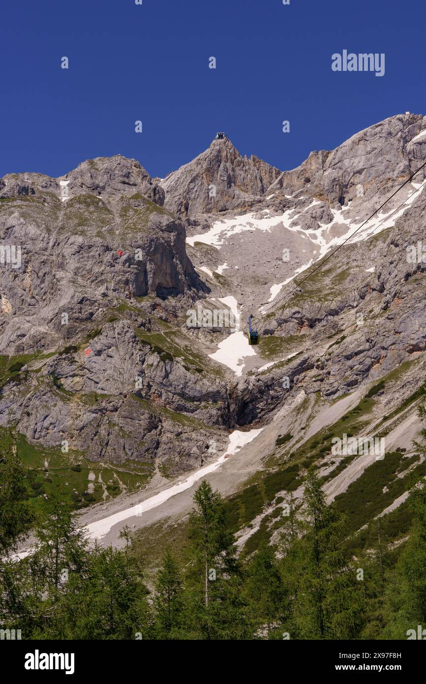 Seilbahn zwischen felsigen, schneebedeckten Bergen und Waldgebieten, zerklüfteten Bergen mit Felswänden und schneebedeckten Gipfeln, Gosau, Österreich Stockfoto