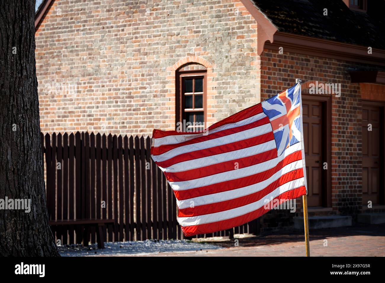 Eine Grand Union Flagge weht im Wind auf der Straße in Colonial Williamsburg, Virginia. Stockfoto Eine Grand Union Flagge weht im Wind auf der Straße in Colonial Williamsburg, Virginia. Stockfoto