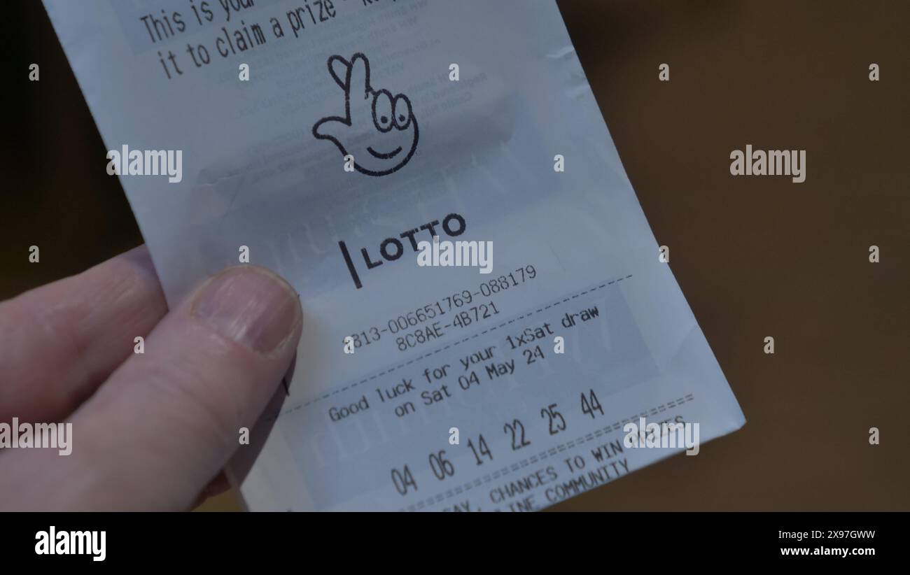 Ein Lotteriescheinkäufer überprüft seine Nummer in der britischen National Lottery. Stockfoto