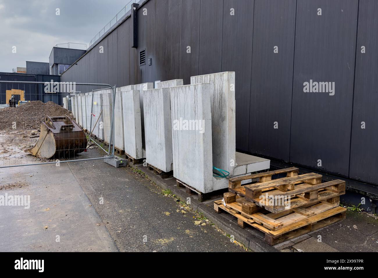 Betonbausteine, leere Holzpaletten und Baggerlöffel auf der Baustelle. Stockfoto