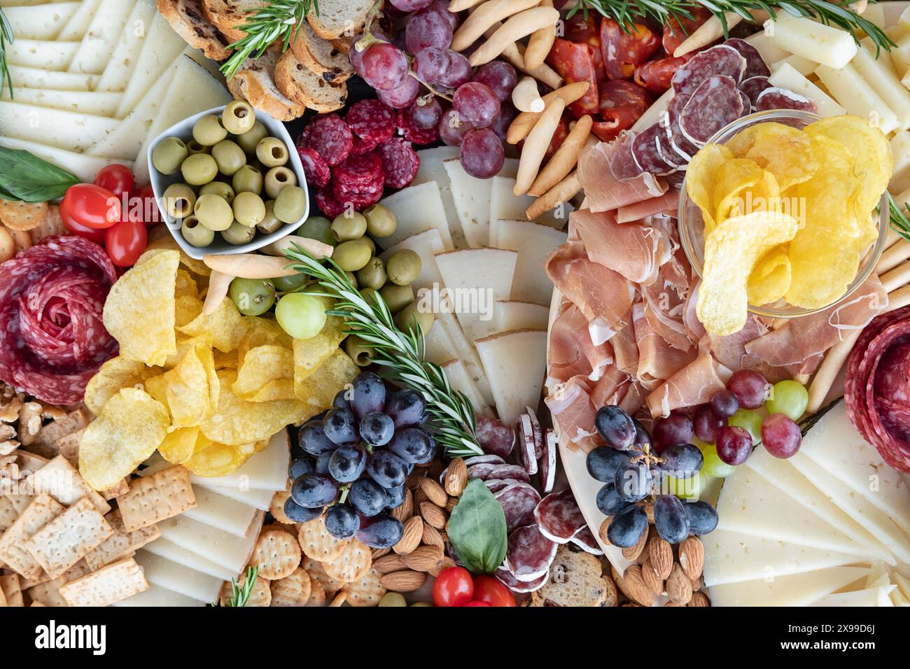 Raffinierte Wurstplatte mit einer Auswahl an Wurstwaren, Käse, Oliven, Crackern, Trauben, Nüsse, Kirschtomaten und frische Rosmarinquellen Stockfoto