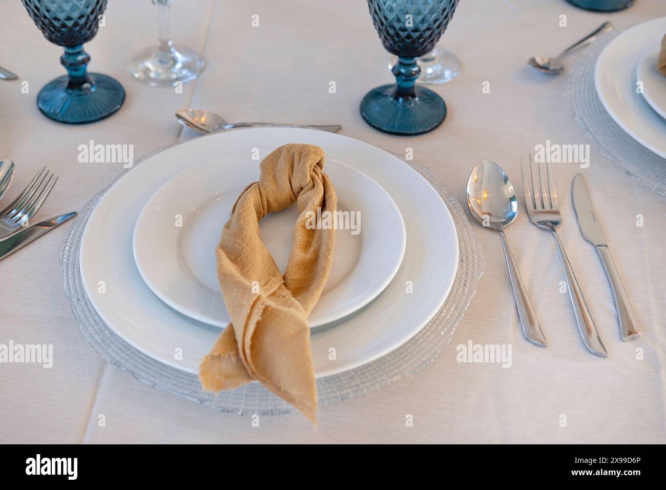 Tischanordnung für formelle Veranstaltungen wie Hochzeiten, Bankette oder gehobene Zusammenkünfte mit weißen Tellern und geknüpfter Stoffserviette Stockfoto