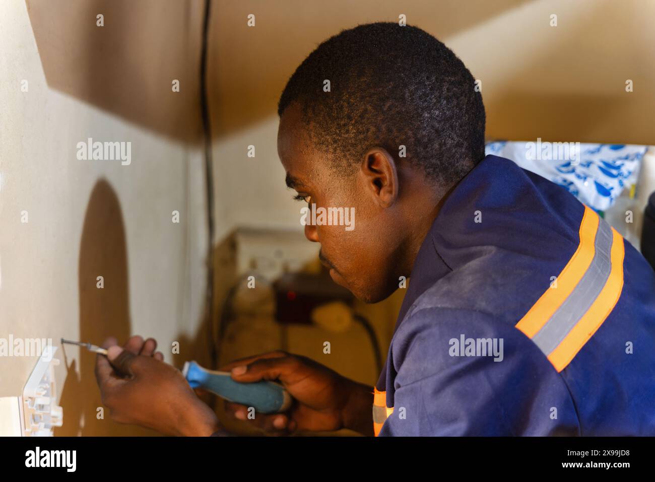 afrikanischer Techniker mit einem Schraubendreher, der Glasfaserterminal in einem Raum für ein Upgrade des Internets installiert Stockfoto