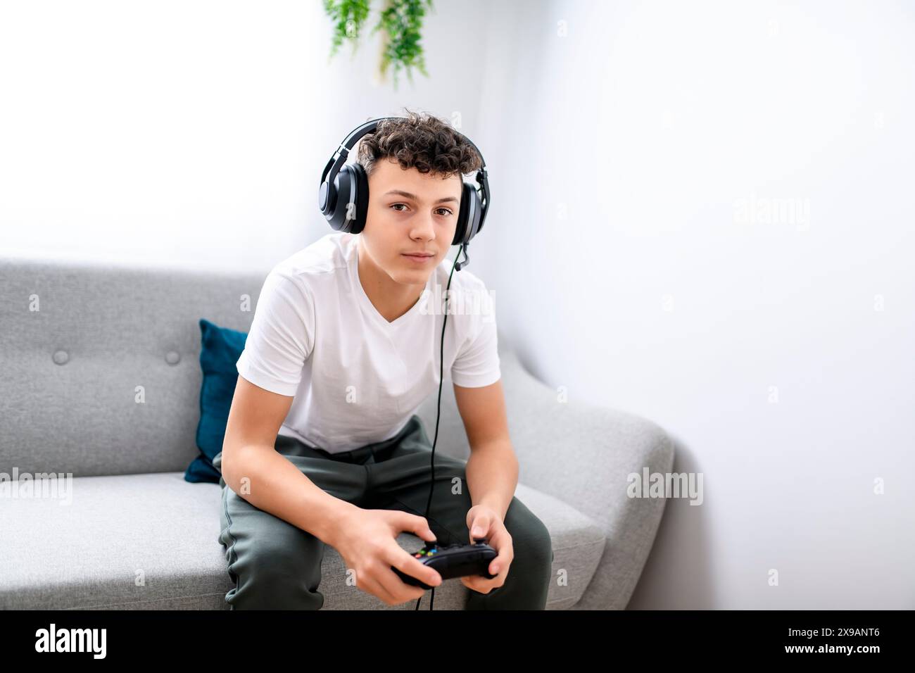 Porträt eines Teenagers, der im Urlaub Videospiele im fernsehen spielt, sitzt zu Hause auf der gemütlichen Couch Stockfoto Porträt eines Teenagers, der im Urlaub Videospiele im fernsehen spielt, sitzt zu Hause auf der gemütlichen Couch Stockfoto
