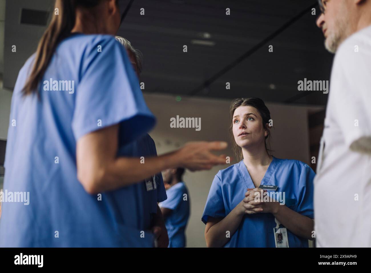 Männliche und weibliche Angehörige der Gesundheitsberufe diskutieren im Krankenhaus Stockfoto