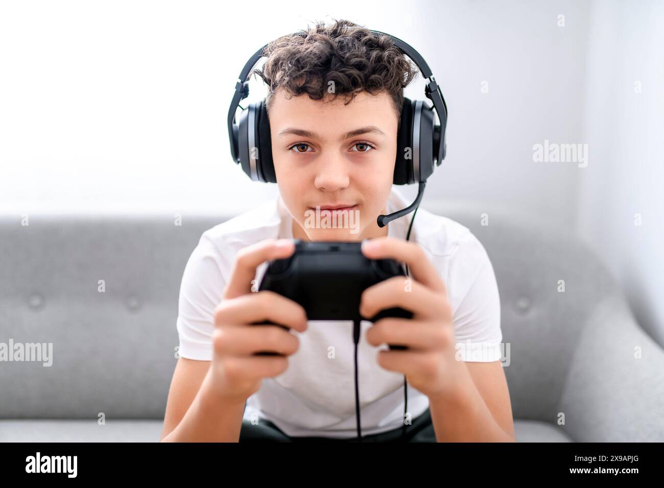 Porträt eines Teenagers, der im Urlaub Videospiele im fernsehen spielt, sitzt zu Hause auf der gemütlichen Couch Stockfoto Porträt eines Teenagers, der im Urlaub Videospiele im fernsehen spielt, sitzt zu Hause auf der gemütlichen Couch Stockfoto