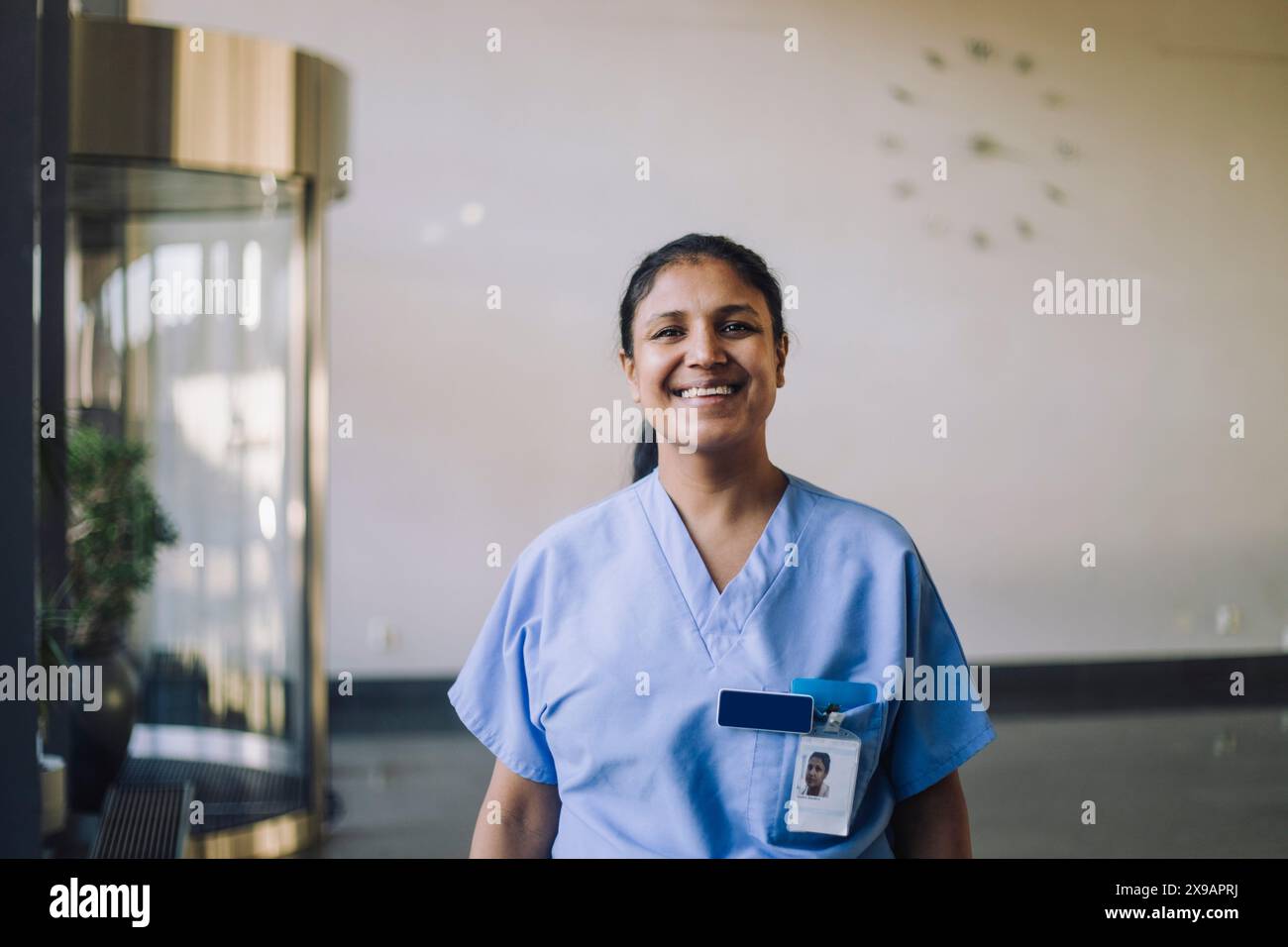 Porträt einer lächelnden Ärztin in blauen Schutten, die im Krankenhaus steht Stockfoto
