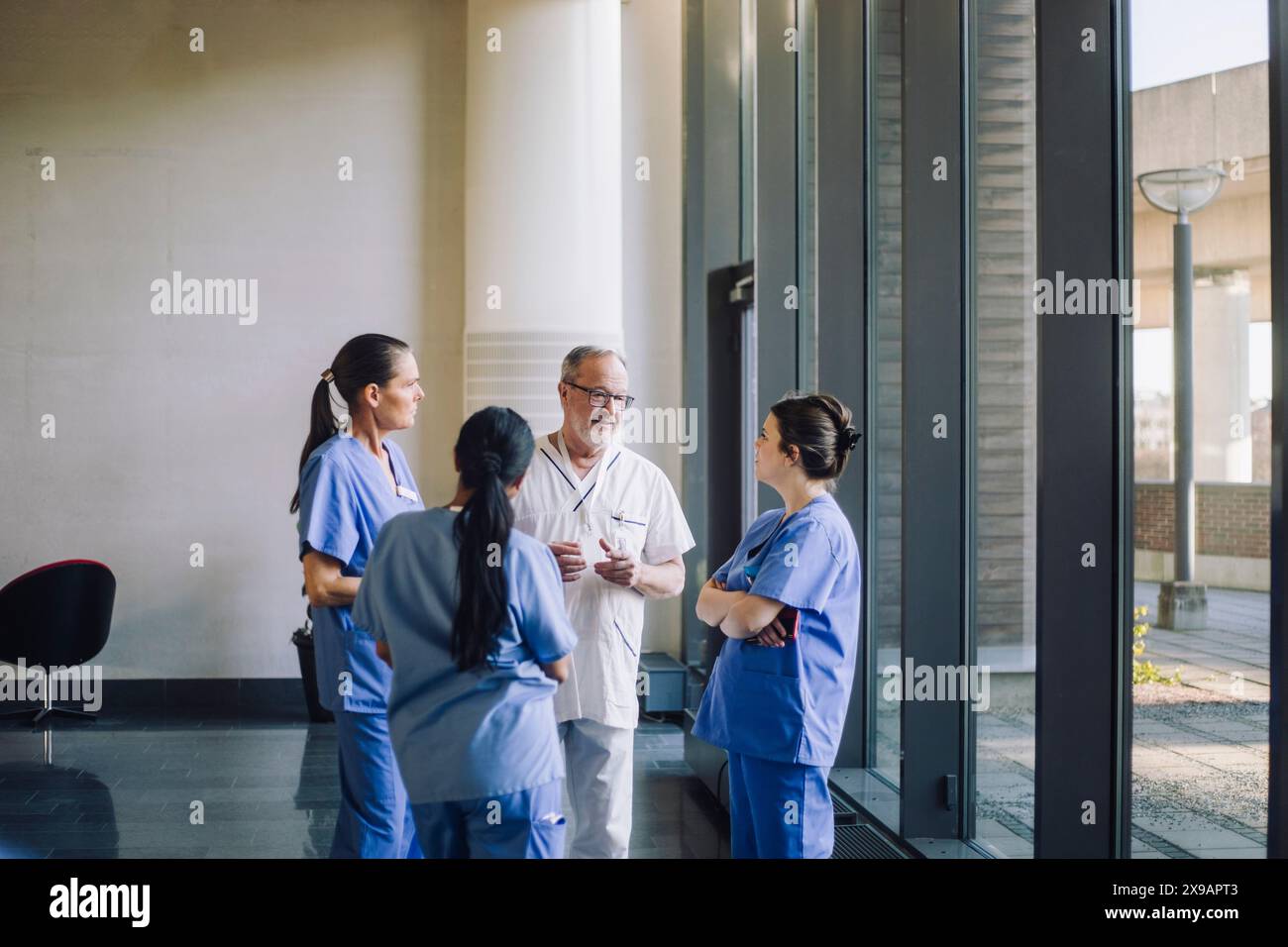 Männliche und weibliche Angehörige des Gesundheitswesens diskutieren während sie in der Lobby des Krankenhauses stehen Stockfoto
