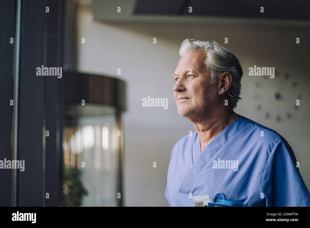 Nachdenklicher Oberarzt in blauem Peeling im Krankenhaus Stockfoto