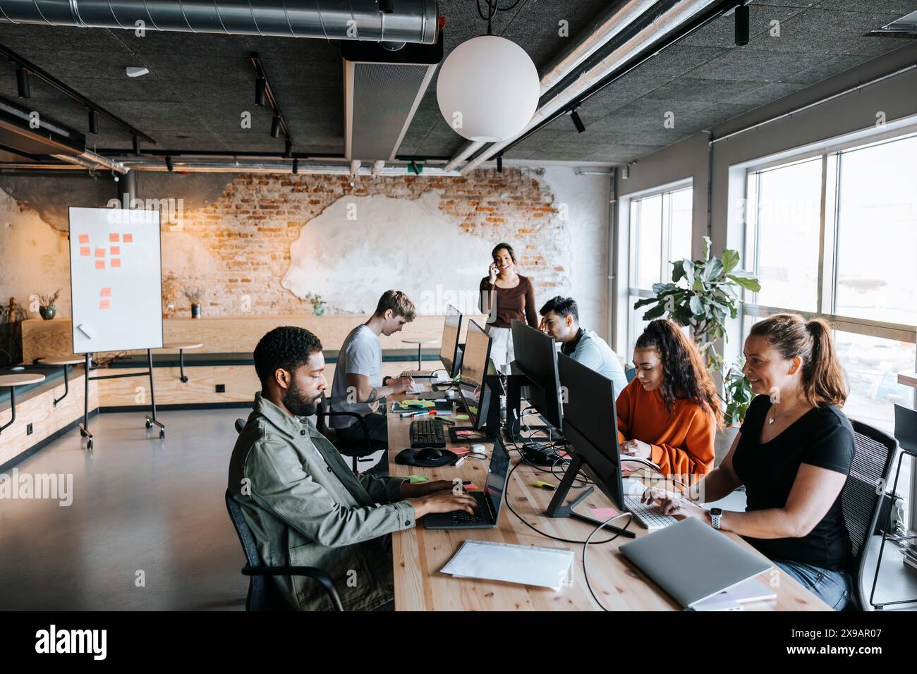 Gruppe männlicher und weiblicher Geschäftsleute, die am Schreibtisch im Coworking Office arbeiten Stockfoto