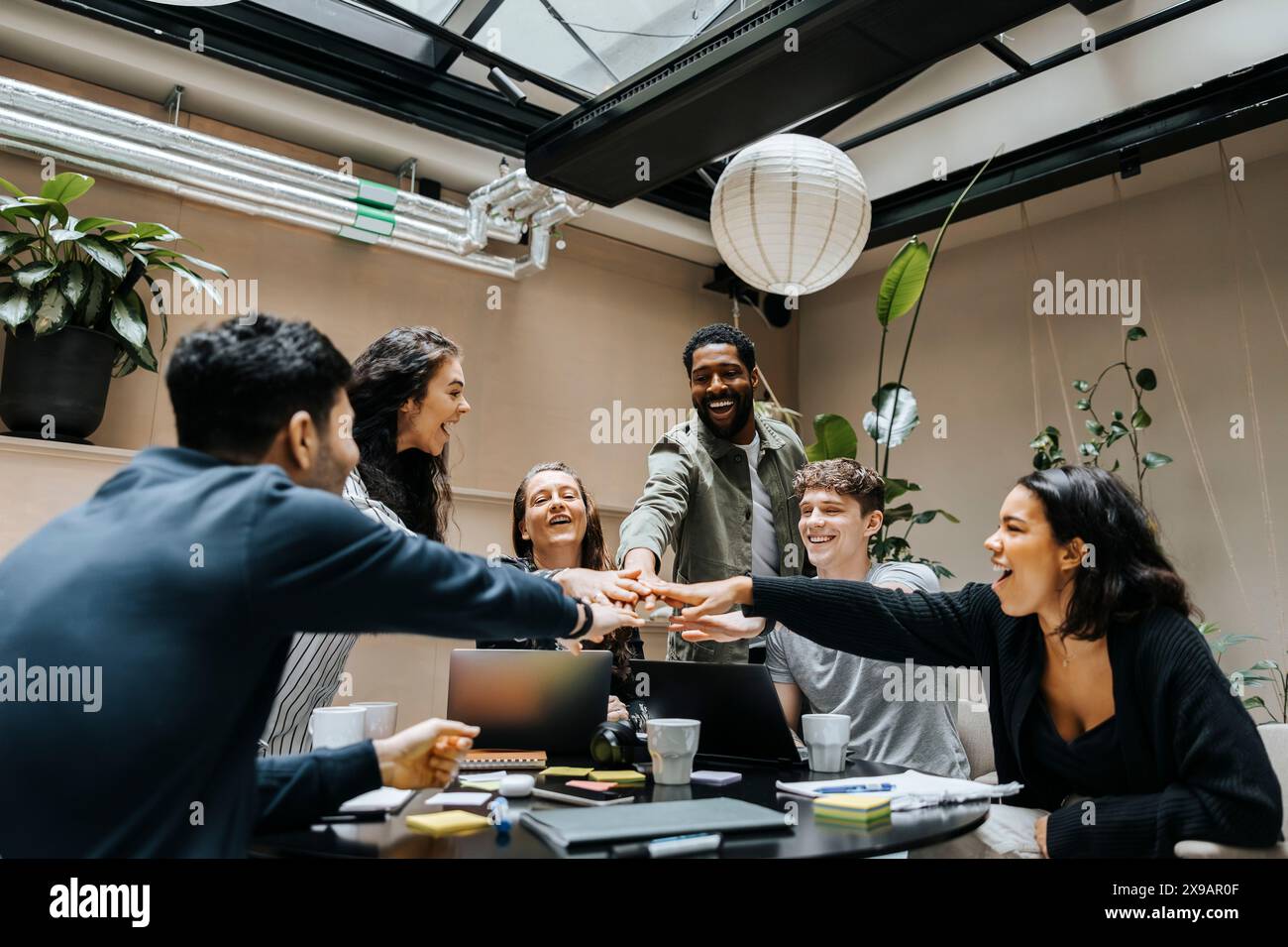 Glückliche Unternehmerinnen und Unternehmerinnen stapeln sich bei Geschäftstreffen im Büro Hände Stockfoto