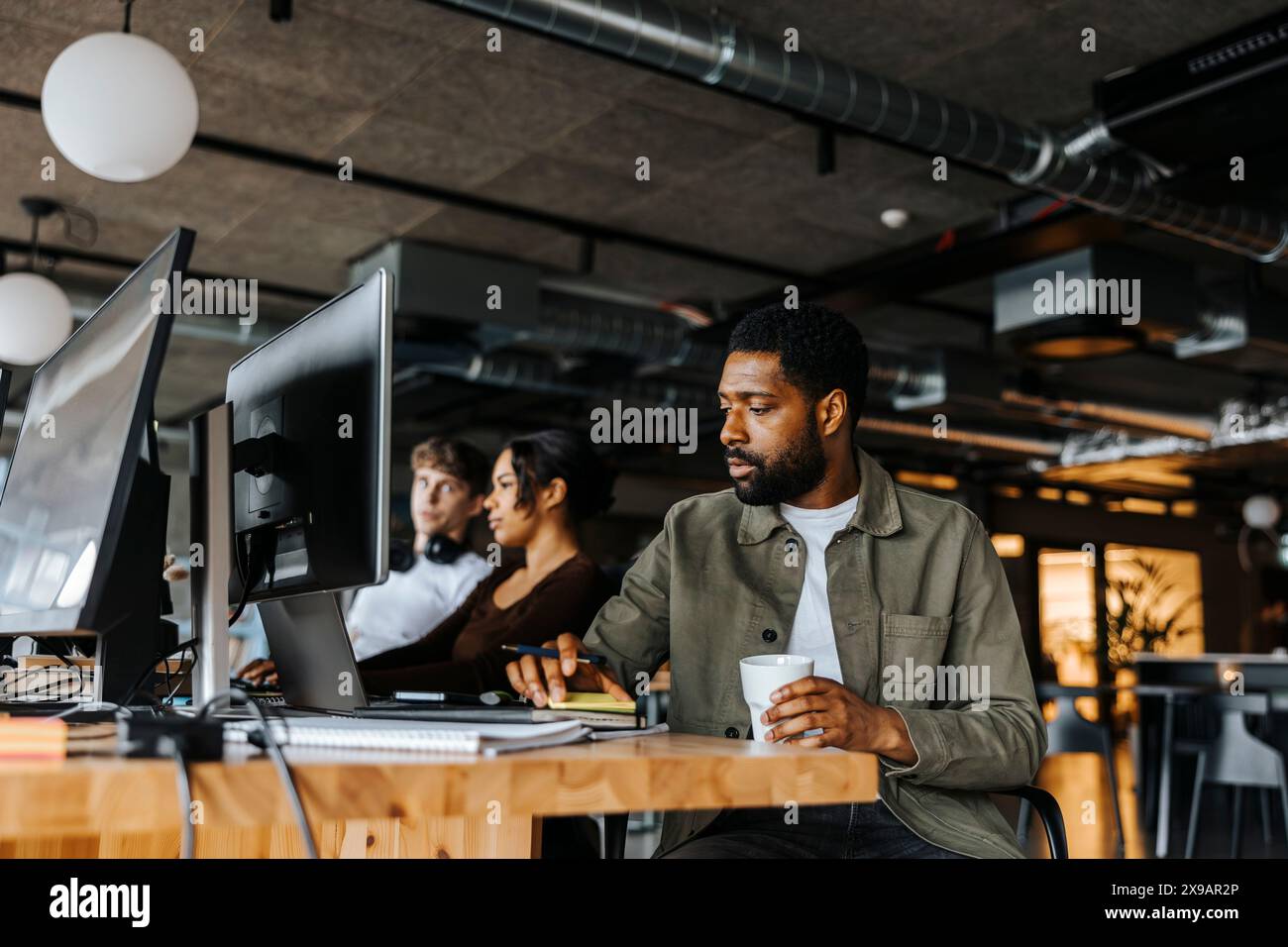 Männlicher Computerprogrammierer, der im technischen Startup-Büro sitzt Stockfoto