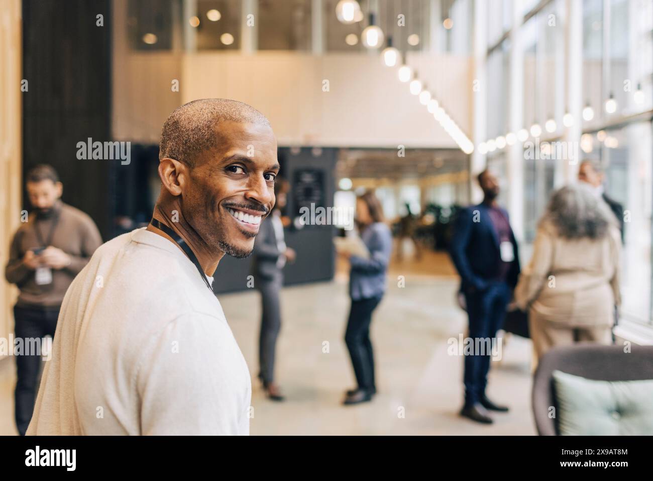 Porträt eines lächelnden männlichen Unternehmers, der im Kongresszentrum über die Schulter schaut Stockfoto