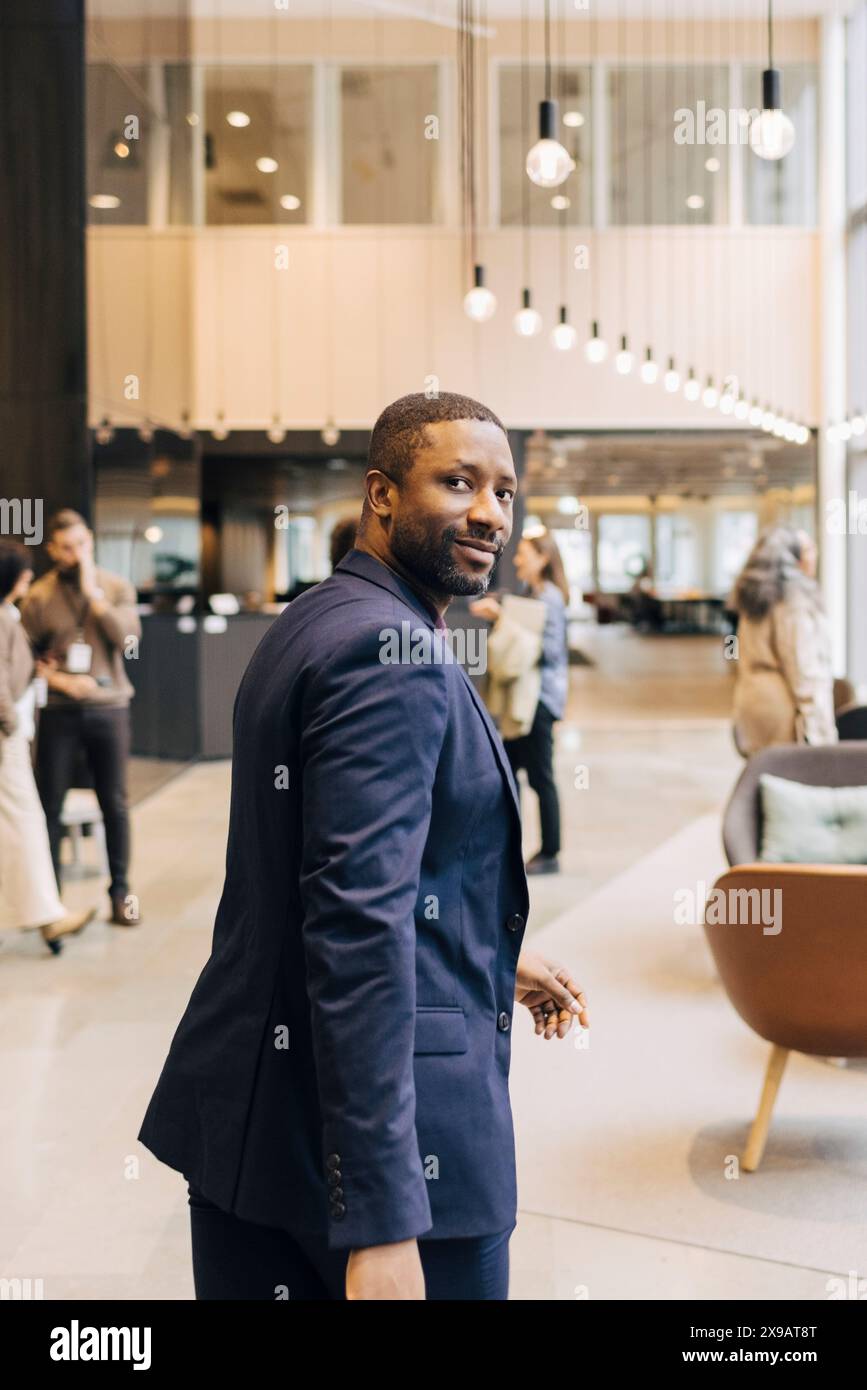 Porträt eines männlichen Unternehmers, der über die Schulter schaut, während er in der Lobby im Convention Center spaziert Stockfoto