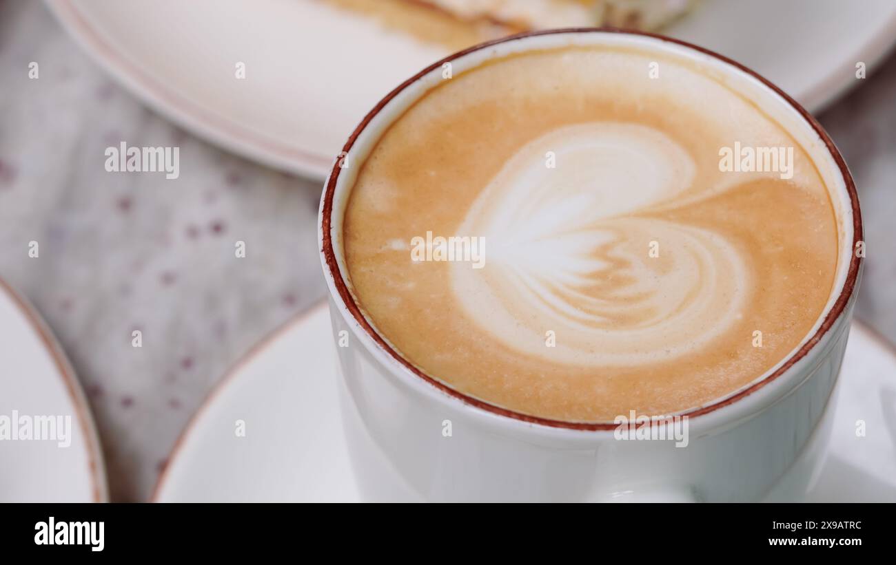 Cremiger Kaffee in einer weißen Tasse auf einem Kaffeetisch, perfekt für ein friedliches Frühstück... Stockfoto