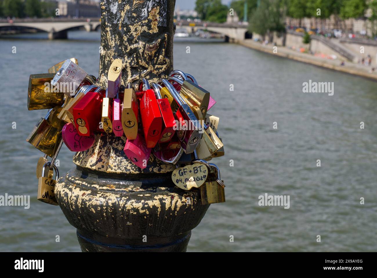 Paris, Frankreich 05.25.2024 Liebesschlösser, die an einem Laternenpfosten auf einer Brücke über die seine befestigt sind. Stockfoto