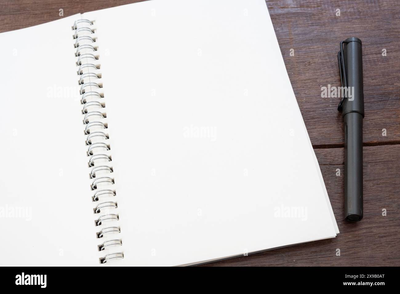 Weißes Papier leeres Buchmockup mit Stift auf Holztisch Stockfoto