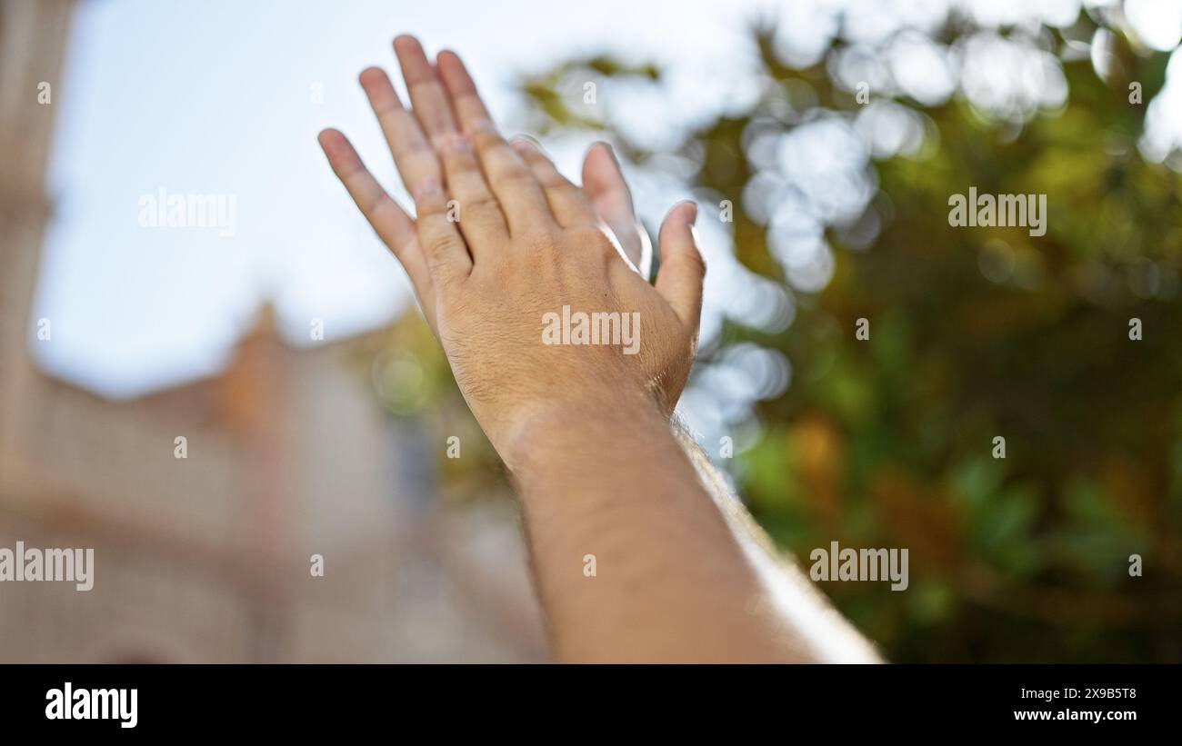 Nahaufnahme der gestreckten Hand des Menschen in einem Naturpark mit verschwommenem Grün im Hintergrund, das die Verbindung mit der Natur darstellt. Stockfoto