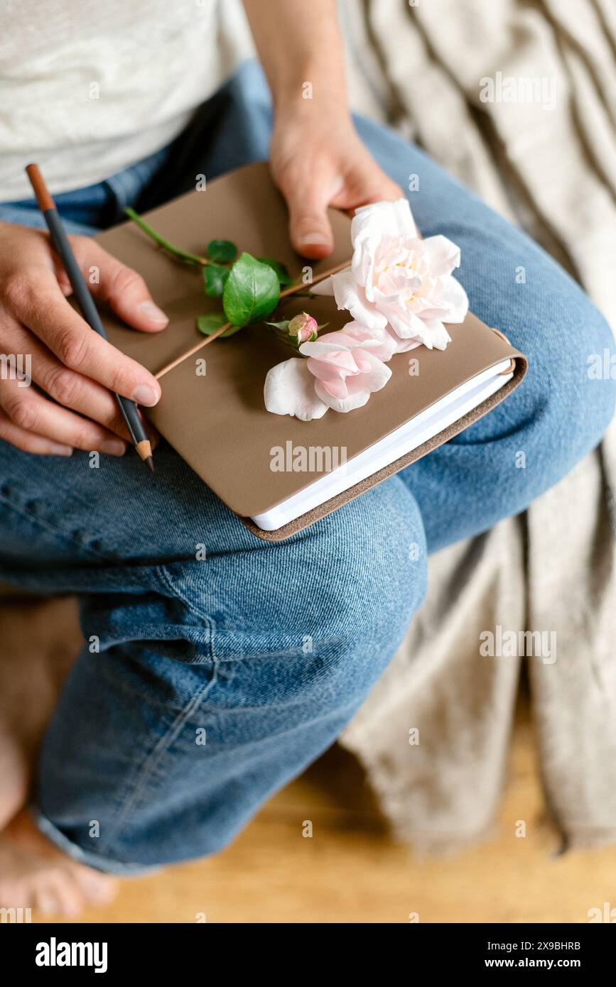 Frau hält einen Notizblock und eine rosa Rose. Stockfoto