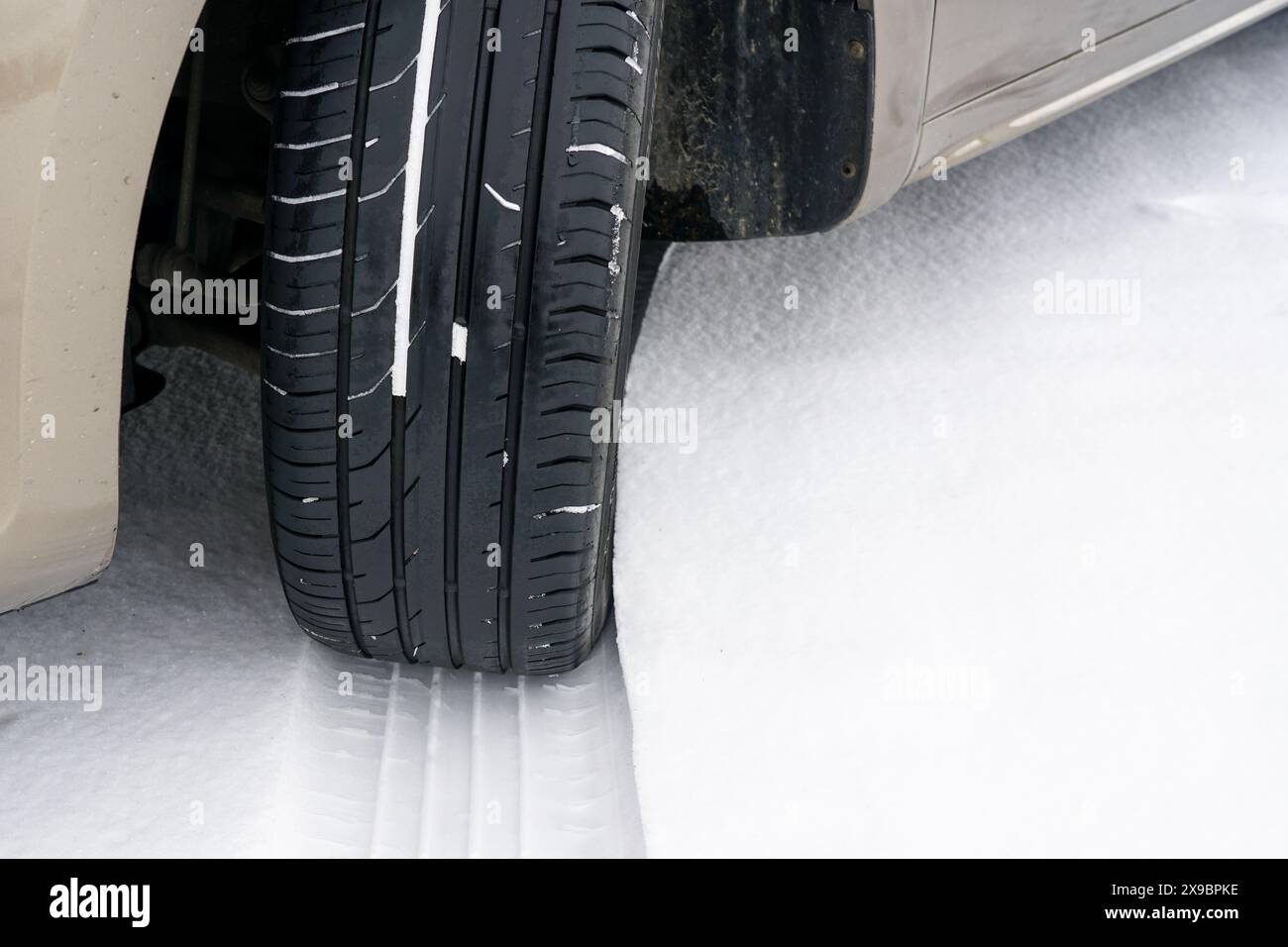 Autorad mit unsicherem Sommerreifen während der Fahrt durch rutschige Schneebahnen im Winter, Sommerreifen im Schnee Stockfoto