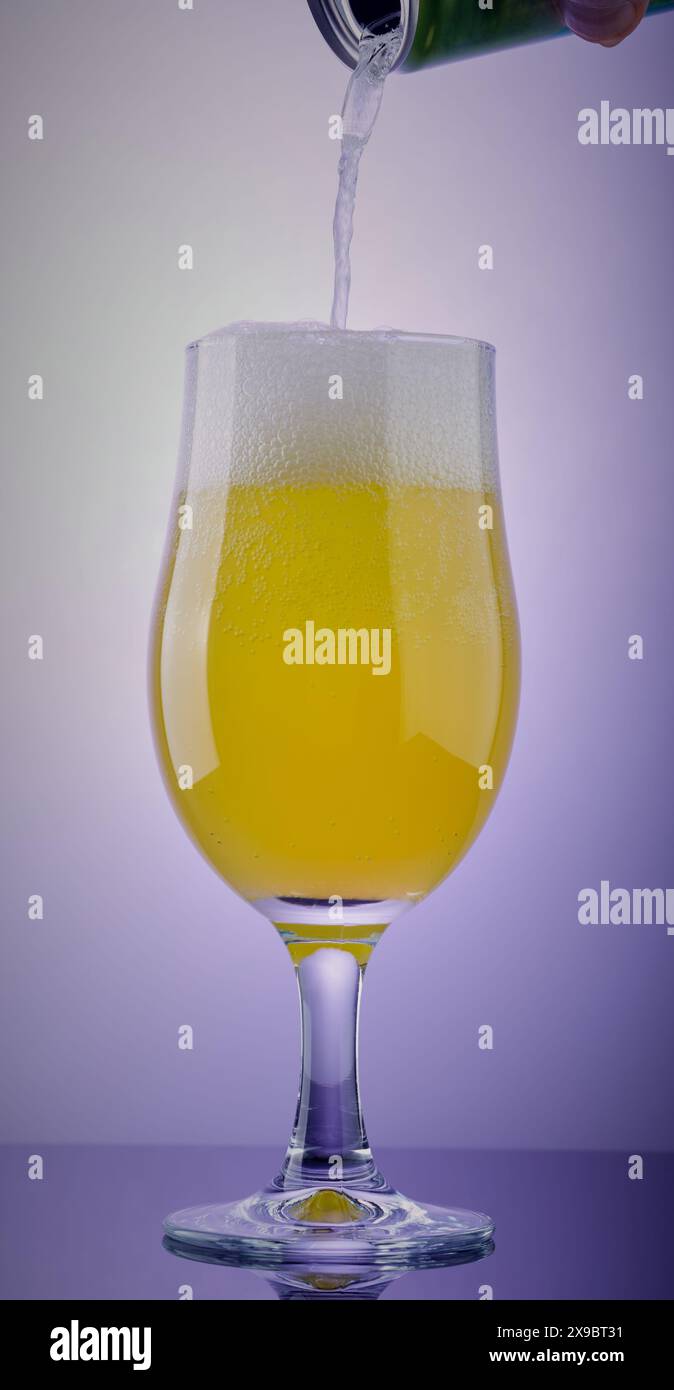 Glas mit kohlensäurehaltigem Getränk, das aus einer Dose darüber hineingepocht wird. Stockfoto