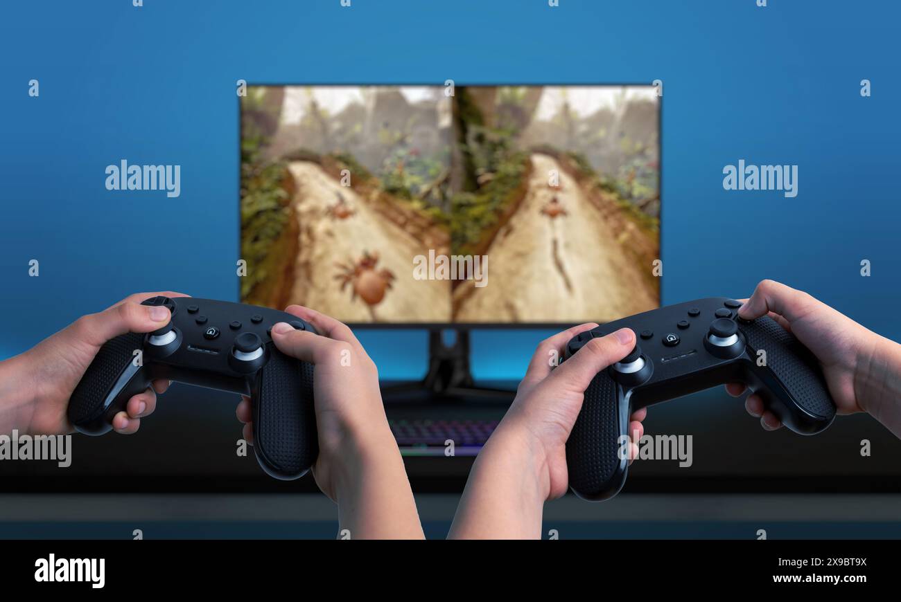 Zwei Spieler, die Gamepads verwenden und ein Spiel auf einem Computer mit geteiltem Bildschirm spielen. Ideal für die Präsentation von Multiplayer-Gaming-Erlebnissen Stockfoto
