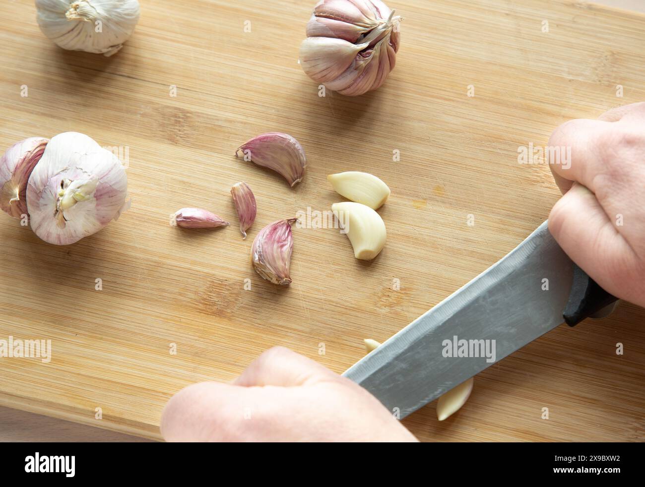 Knoblauchzehen mit einem Messer zerquetscht Stockfoto