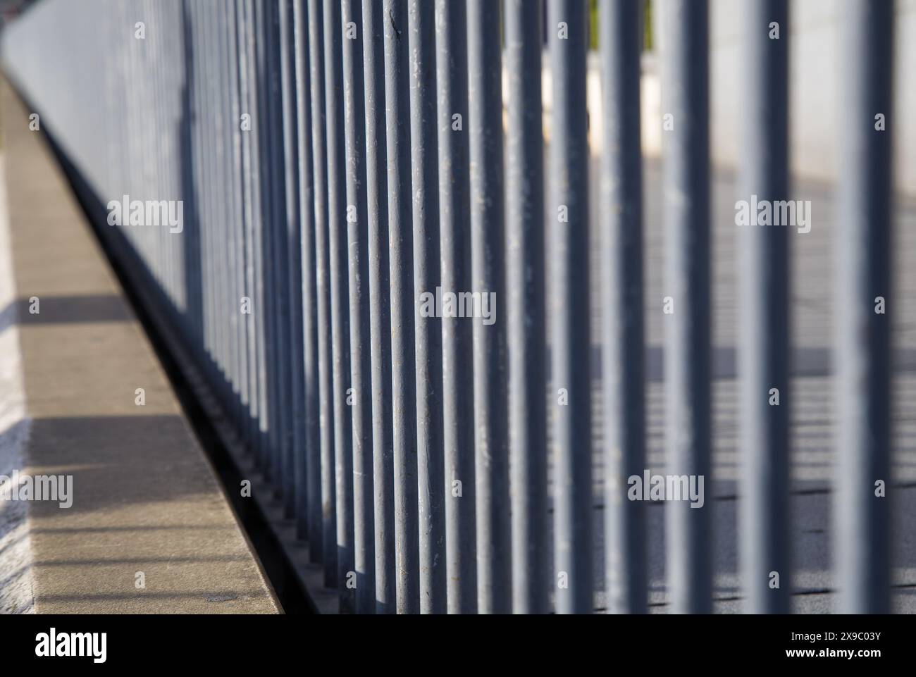 Graue Metallbarriere am Rande des Fußwegs Stockfoto