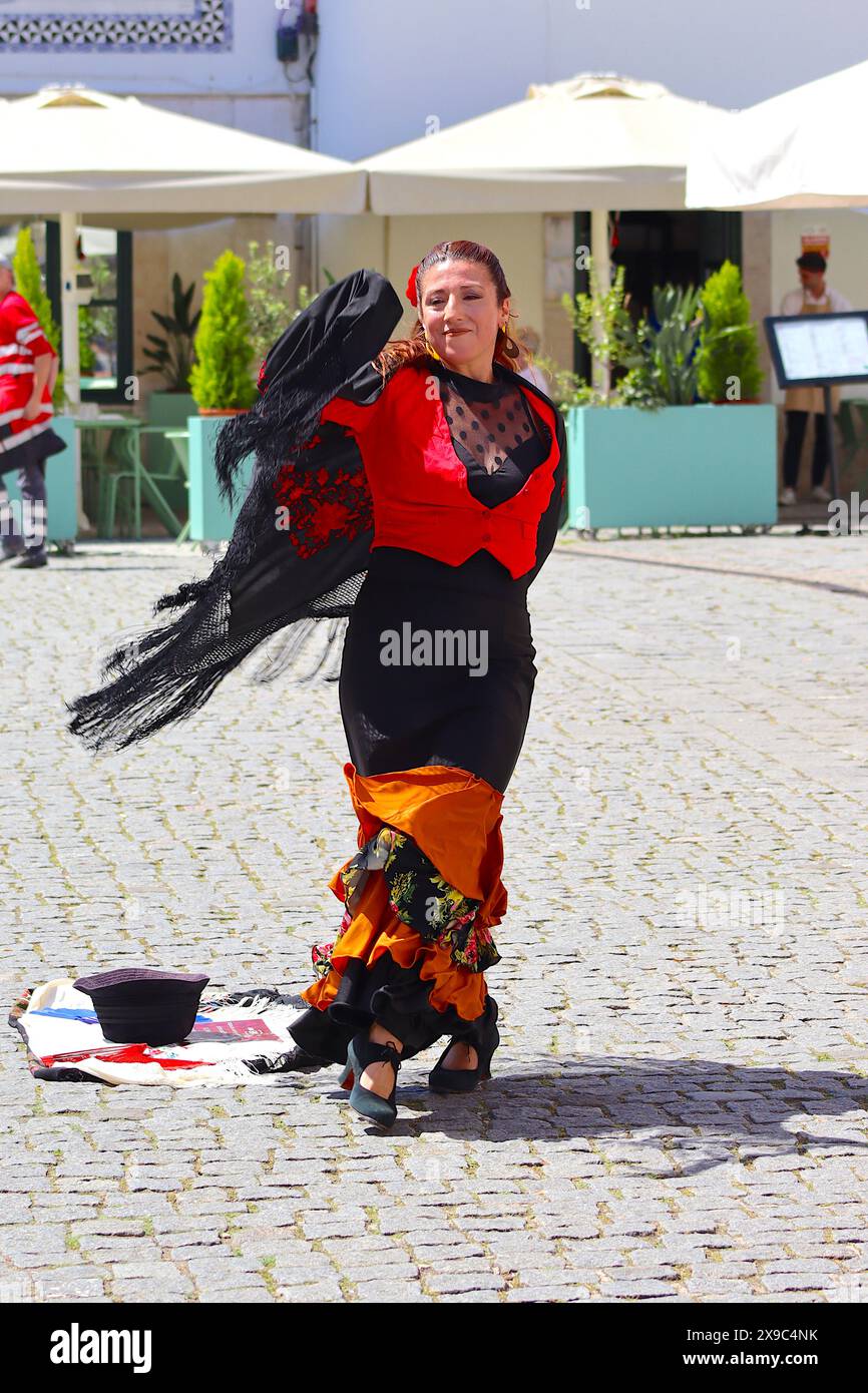 Gloria Rios trägt ein traditionelles Flamenco-Kostüm und spielt unter der Mittagshitze in einer Straße in Lissabon zu traditioneller Musik und unterhält die Zuschauer. Stockfoto