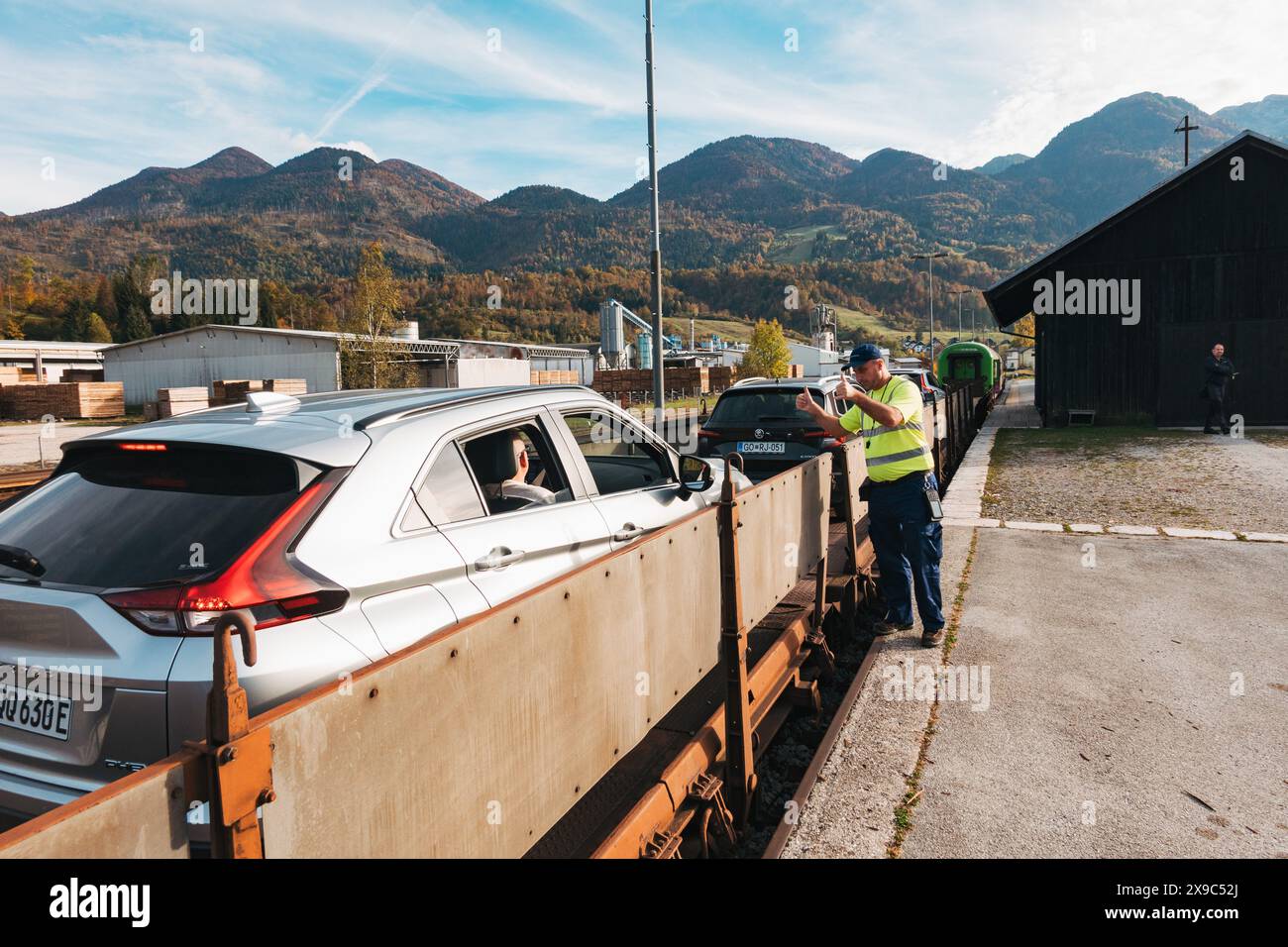 Ein Eisenbahnmitarbeiter hält einen Daumen hoch zu einem Wagen, der in Bohinjska Bistrica auf einen Wagen geladen ist, bereit für die Fahrt nach Most na Soči, Slowenien Stockfoto