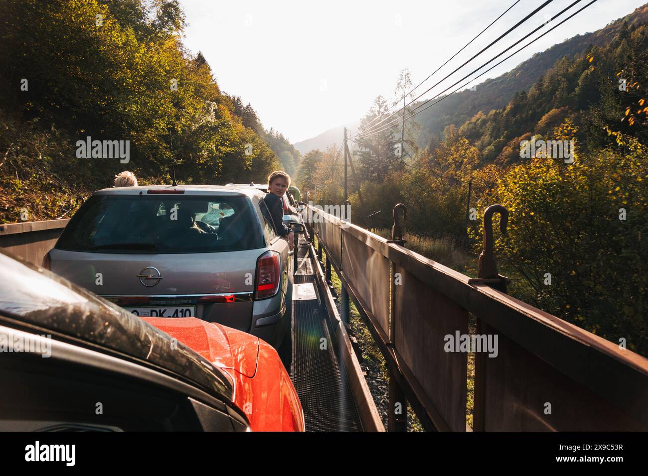Zwei Jungen lehnen sich aus einem Autofenster, während sie auf dem Rücksitz eines Eisenbahnwaggons durch Tunnel und Schluchten in Slowenien fahren Stockfoto