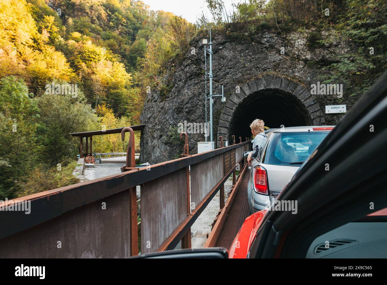 Ein Junge lehnt sich aus einem Autofenster, während er auf der Rückseite eines Eisenbahnwaggons durch Tunnel und Schluchten in Slowenien fährt Stockfoto