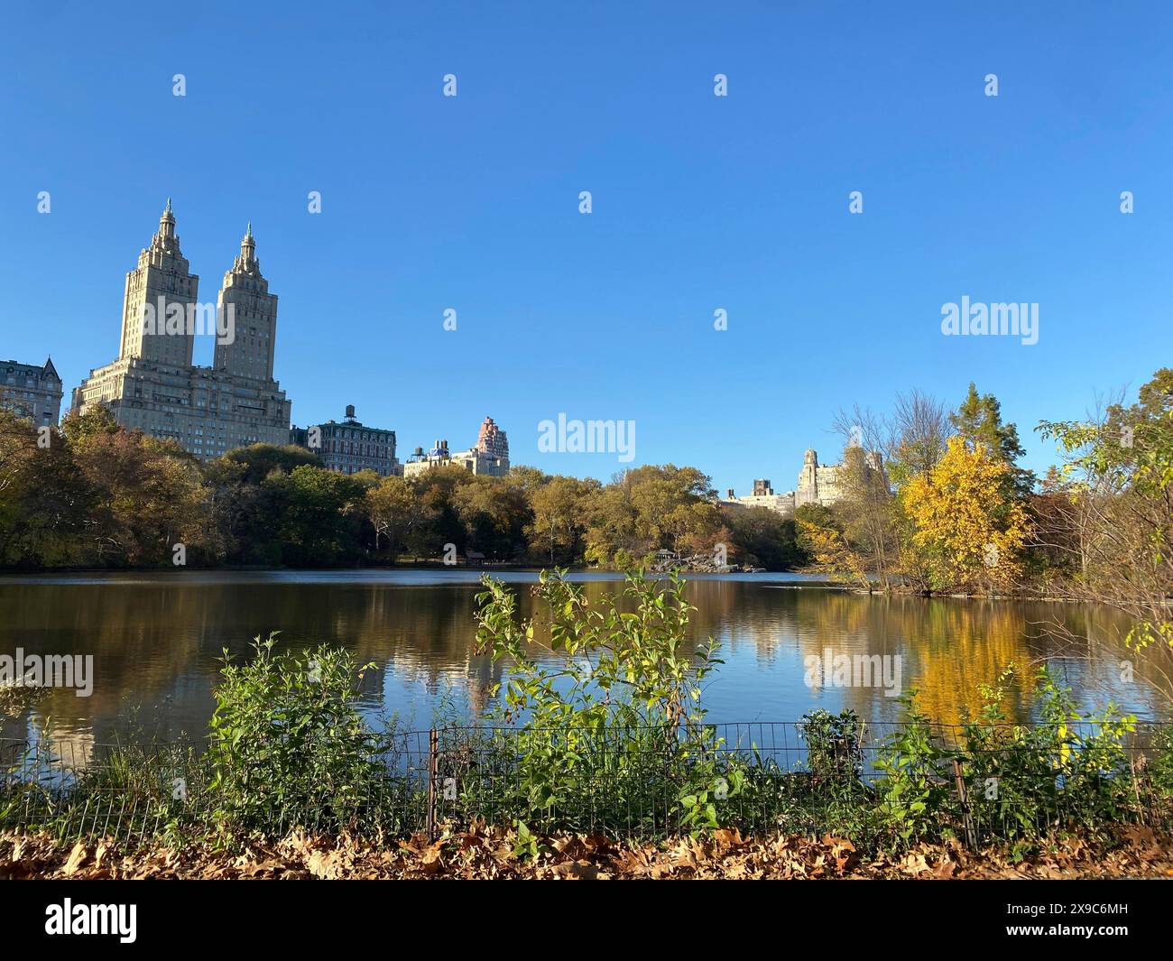 Ein ruhiger See im zentralen Park mit reflektierenden Wolkenkratzern und Herbstbäumen im Hintergrund, die Skyline von New york mit beeindruckenden Wolkenkratzern Stockfoto