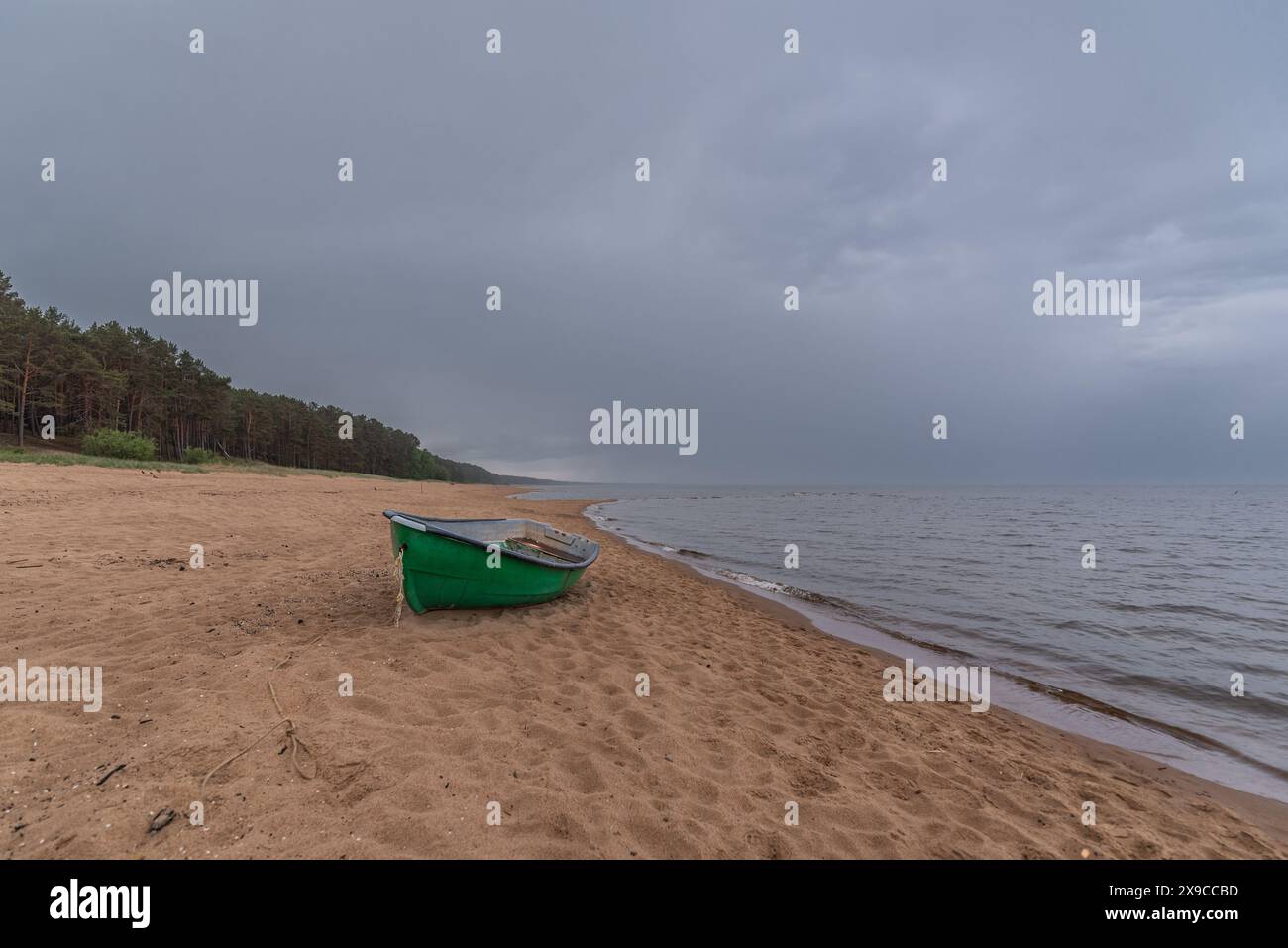 Sandstrand der Ostsee mit Fischerboot am Ufer in Saulkrasti, Lettland an regnerischen Tagen Stockfoto