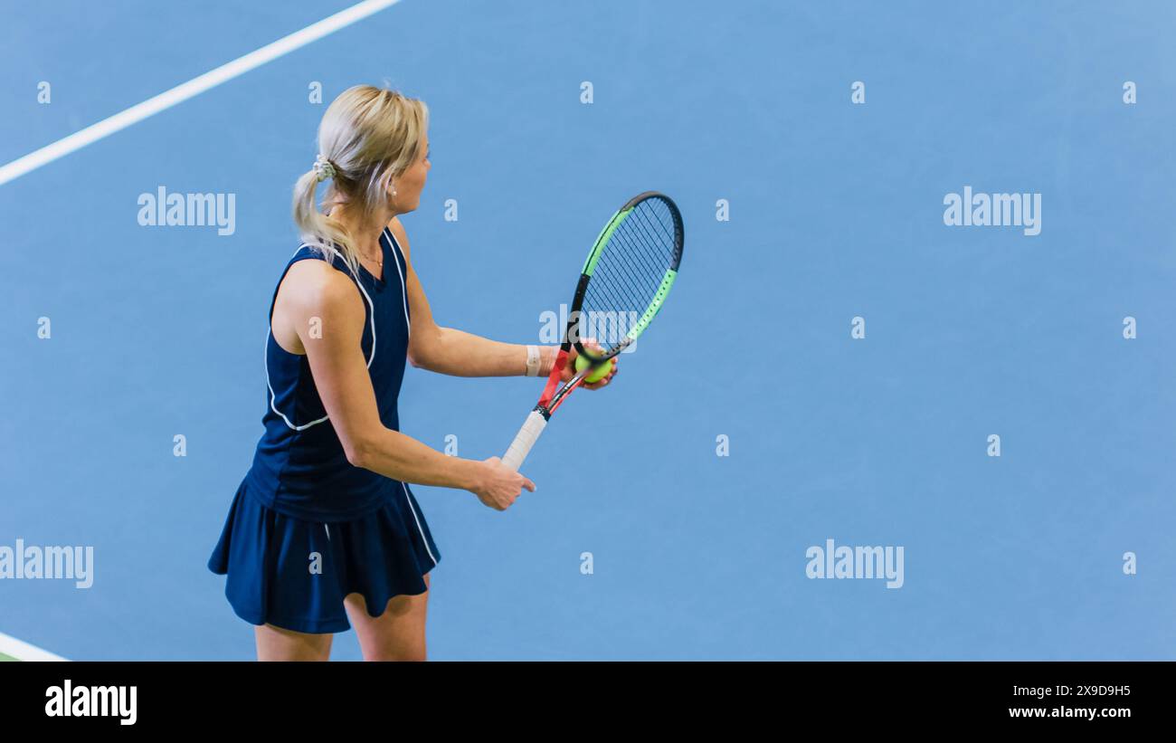Weibliche Tennisspielerin, die gerade im Einsatz ist, indem sie Ball mit einem Racquet während des Meisterschaftsspiels schlägt. Technische Frau Profi-Athletin bereitet sich auf Strike vor. World Sports Turnier. Hochwinkelaufnahme. Stockfoto