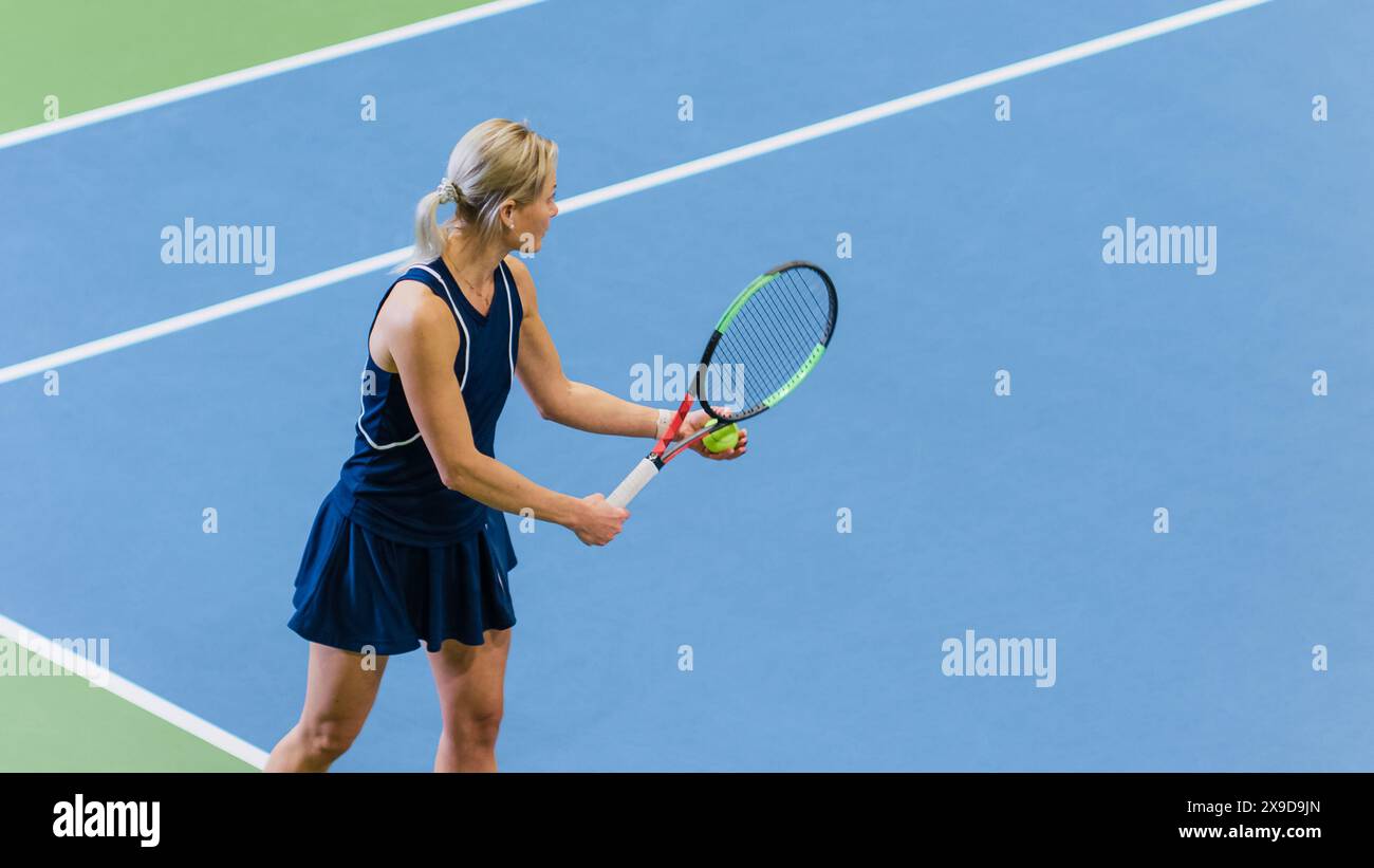 Weibliche Tennisspielerin, die gerade im Einsatz ist, indem sie Ball mit einem Racquet während des Meisterschaftsspiels schlägt. Technische Athletin, die sich auf Strike vorbereitet. World Sports Turnier. High-Angle Medium Shot Foto. Stockfoto