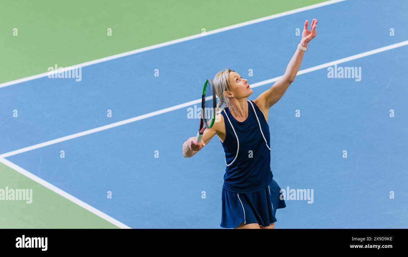 Tennisspielerin, die gerade im Einsatz ist, indem sie während des Meisterschaftsspiels einen Ball in die Luft wirft. Technische Athletin, die sich auf Strike vorbereitet. World Sports Turnier. Großes Foto Mit Mittlerem Winkel. Stockfoto