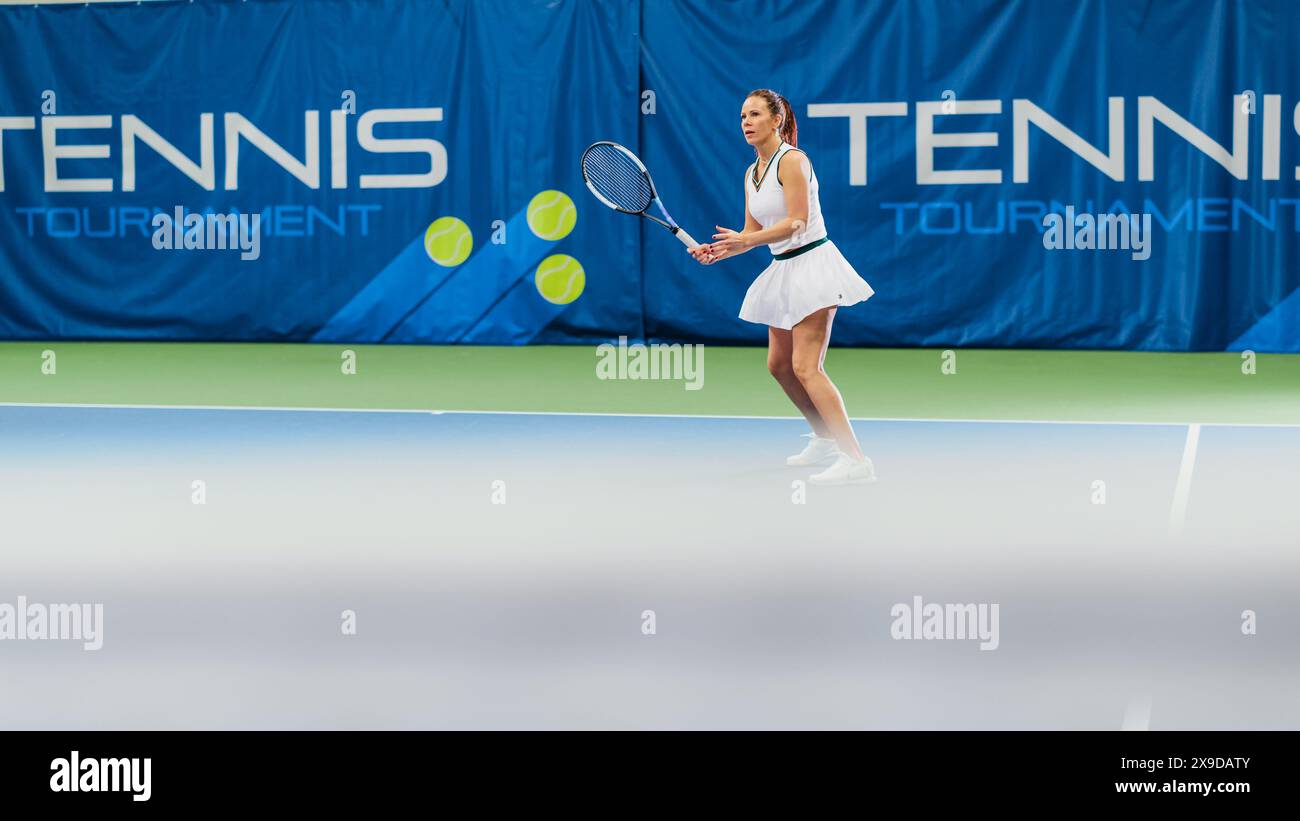 Tennisspielerin, die während des Meisterschaftsspiels Ball mit einem Racquet ansieht. Die Technikerin Athlete erhält und landet den perfekten Volley-Schuss. World Sports Turnier. Weitwinkelfoto. Stockfoto