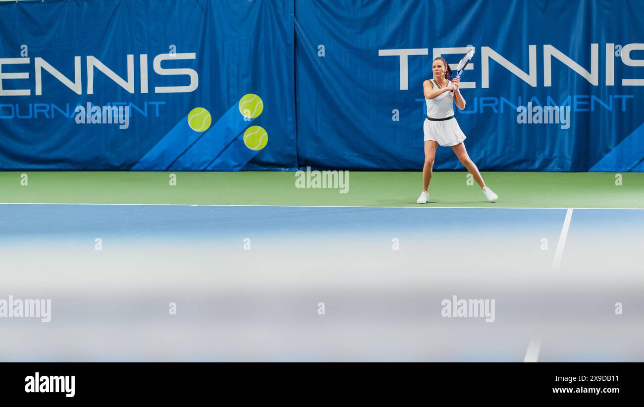 Tennisspielerin, die während des Meisterschaftsspiels den Ball mit einem Racquet trifft. Die Technikerin Athlete erhält und landet den perfekten Volley-Schuss. World Sports Turnier. Weitwinkelfoto. Stockfoto