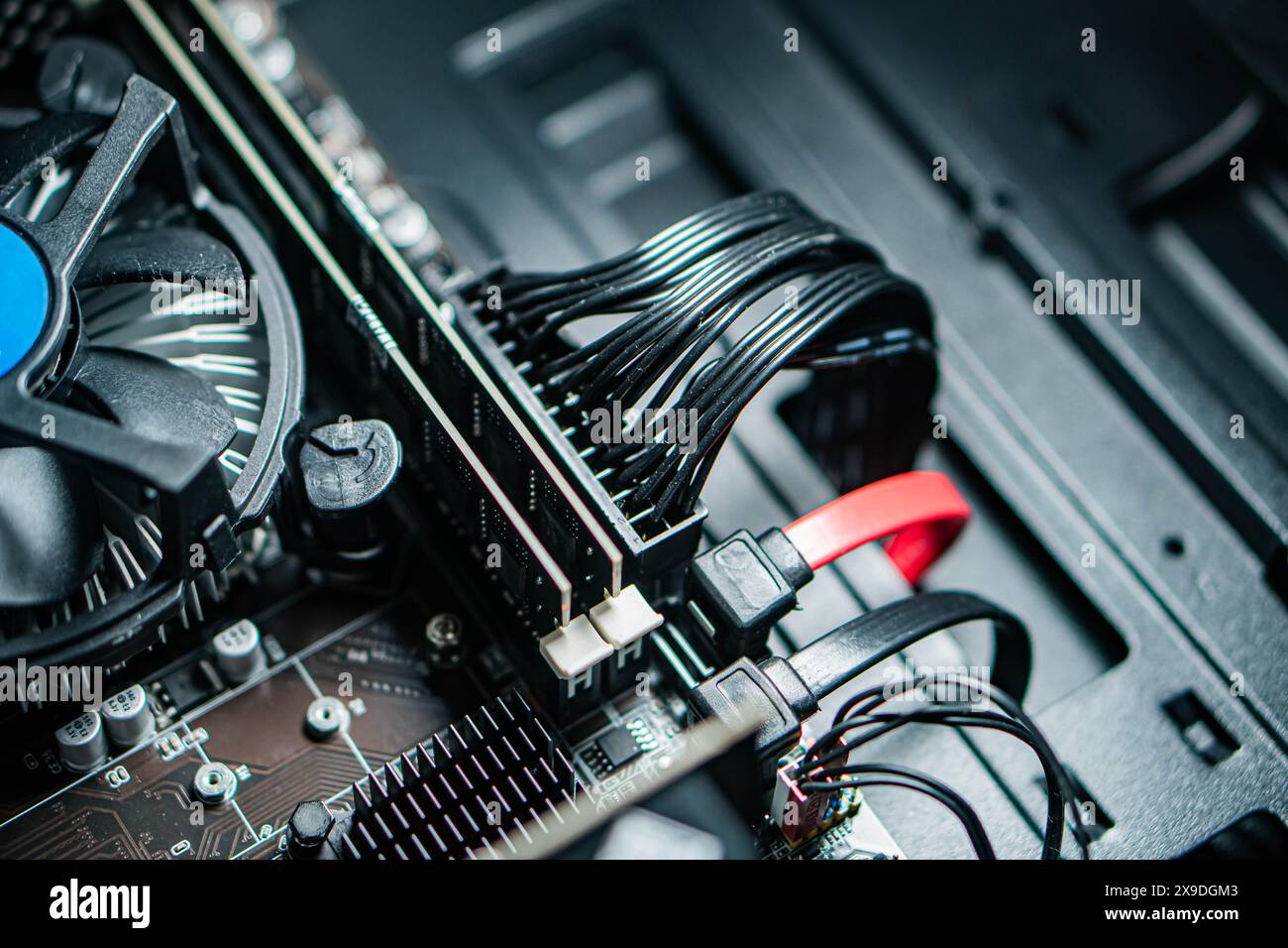 Nahaufnahme der Hardware-Komponenten des Computers, einschließlich eines Lüfters, Kabeln und einer Hauptplatine in einem Computergehäuse. Stockfoto