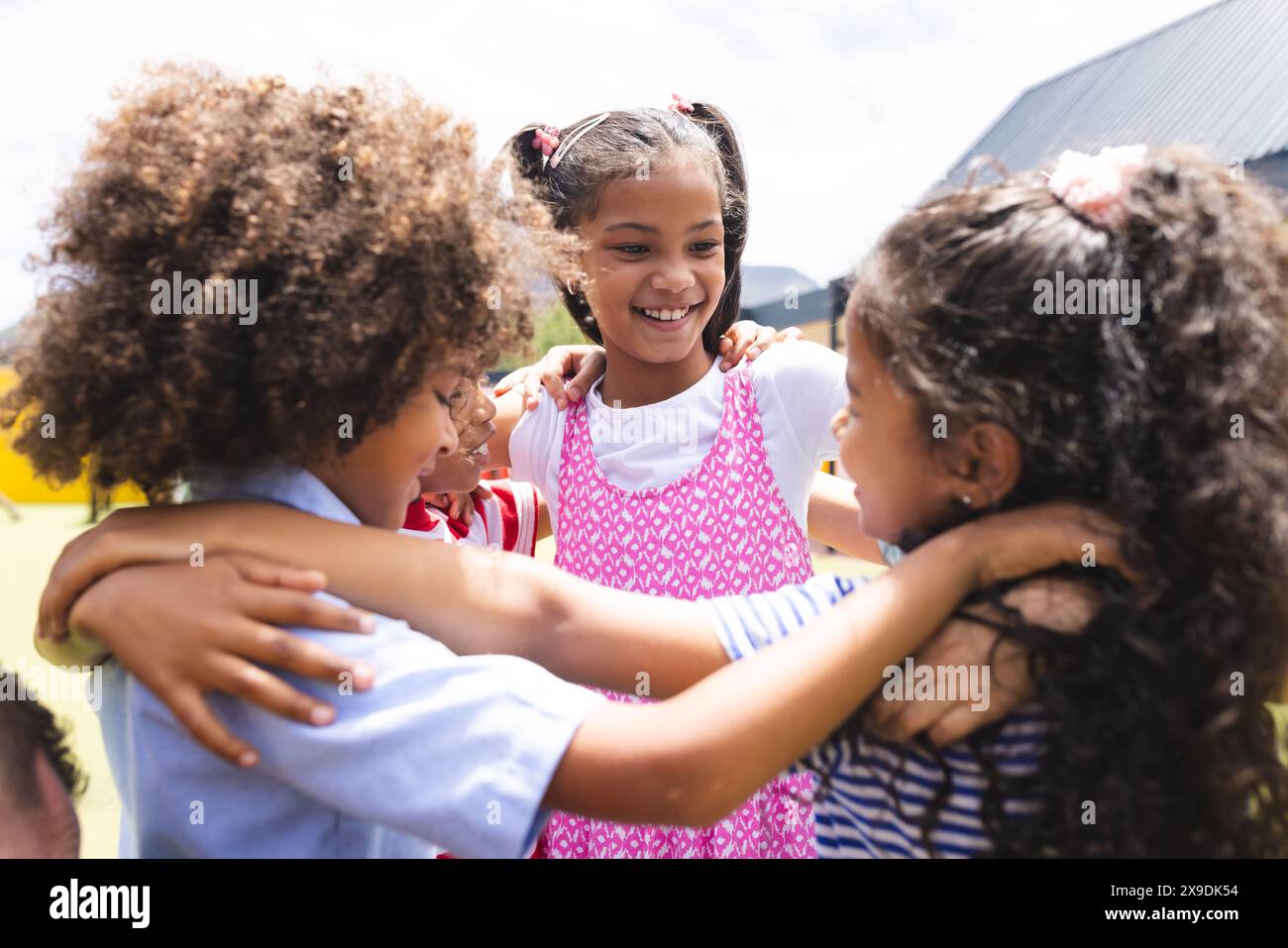 In der Schule umarmen und lachen verschiedene junge Schüler draußen Stockfoto