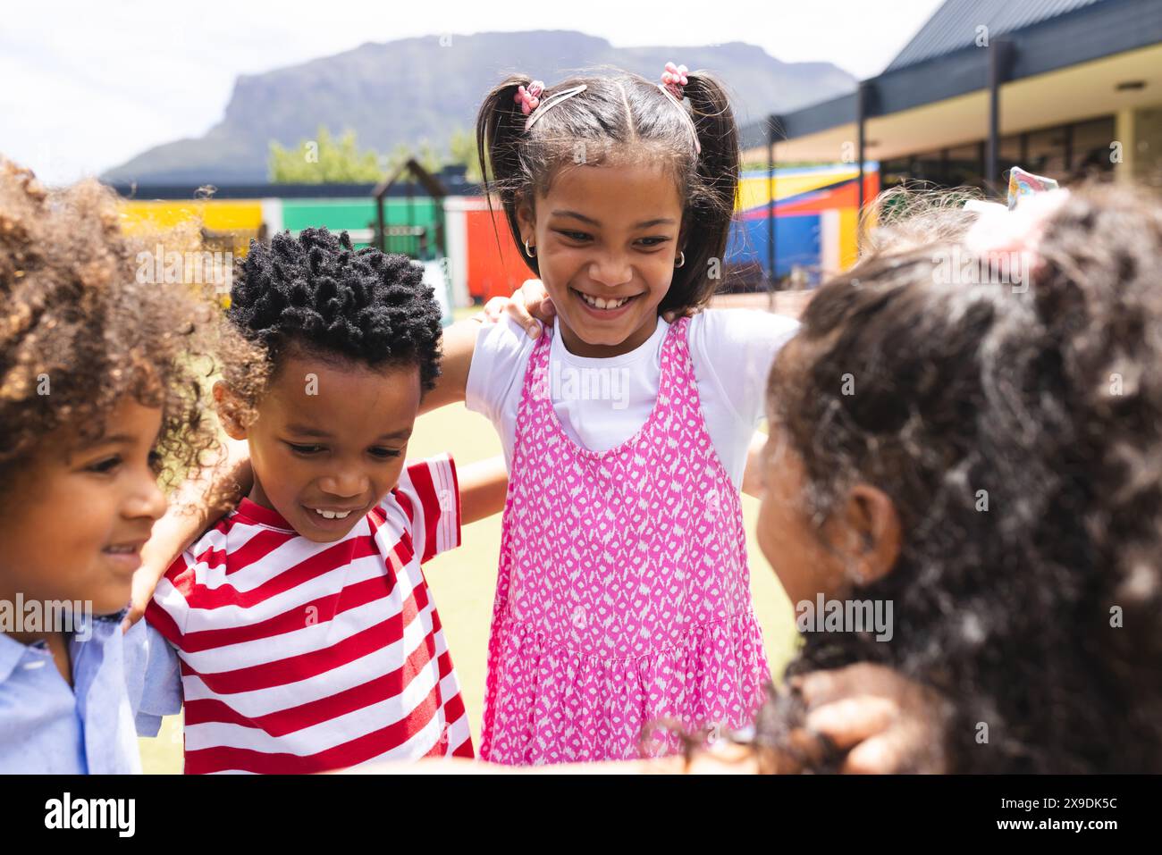In der Schule drängen sich verschiedene Kinder draußen zusammen und lächeln Stockfoto