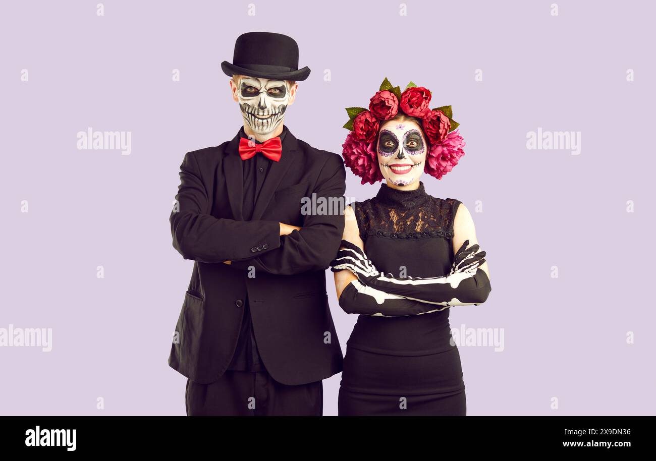 Das niedliche Zombie-Mädchen im Pfingstrosenkranz und ihr Freund mit dem Schädel im Gesicht feiern Halloween. Stockfoto